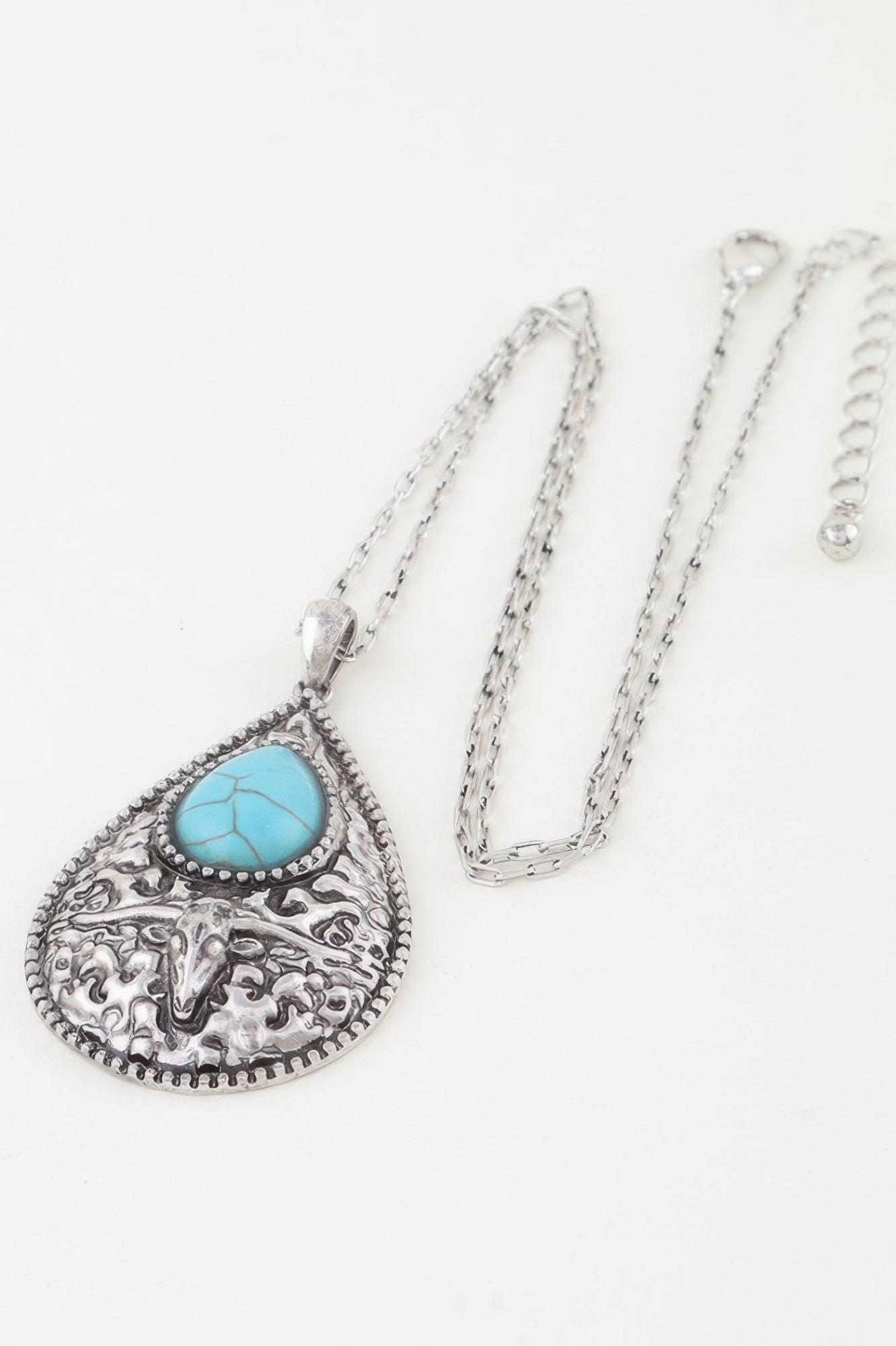Turquoise bull teardrop necklace pendant on chain, ornate silver filigree side view