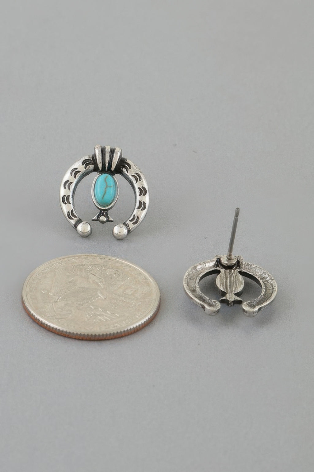 Turquoise oval stud with silver-tone horseshoe frame, shown with coin size