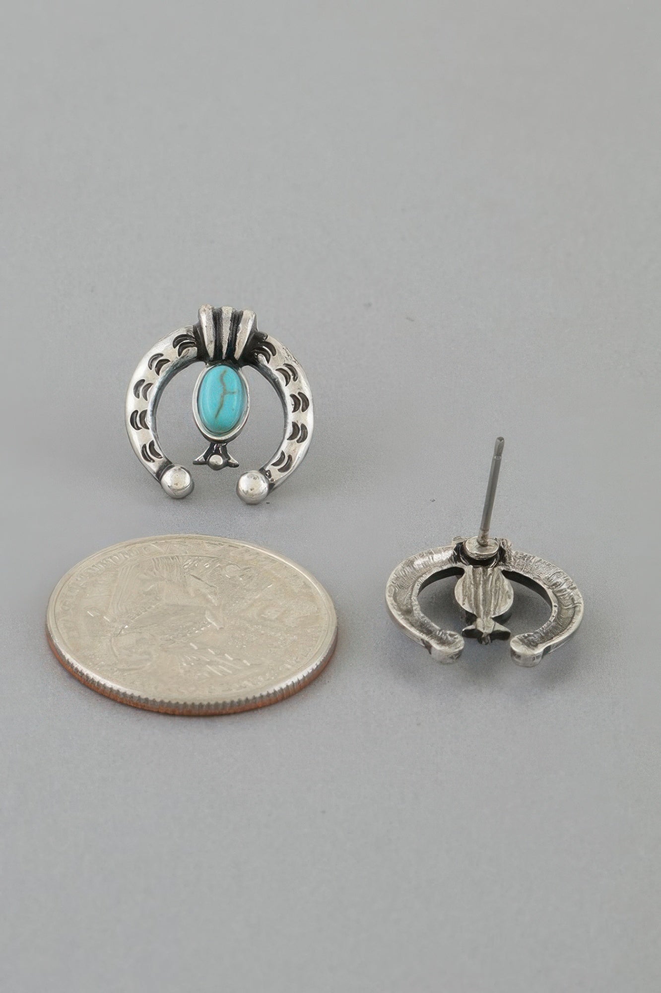 Turquoise oval stud with silver-tone horseshoe frame, shown with coin size