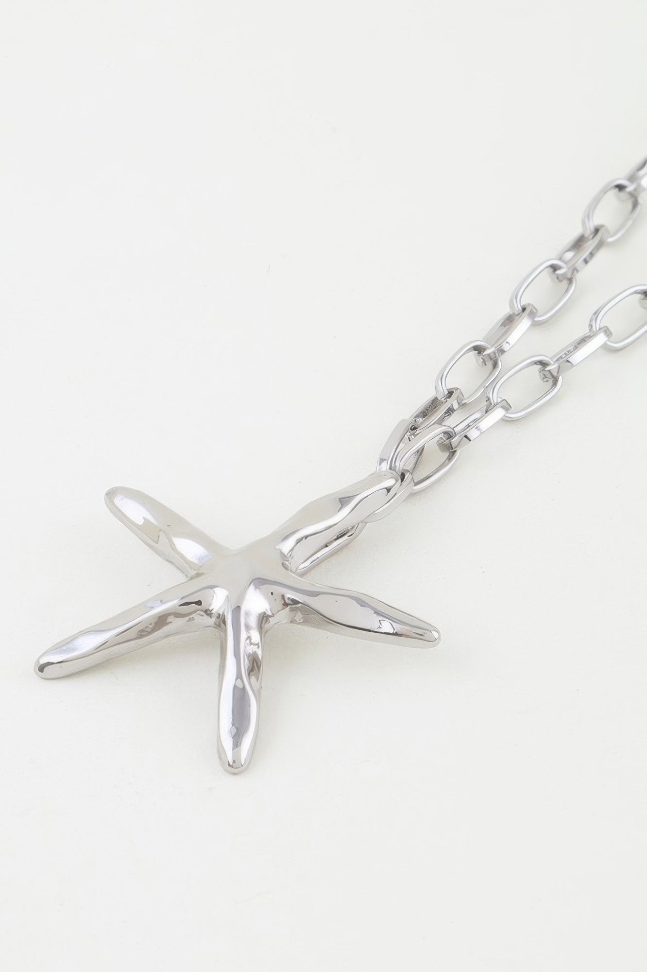 Silver starfish pendant close-up on oval link chain necklace