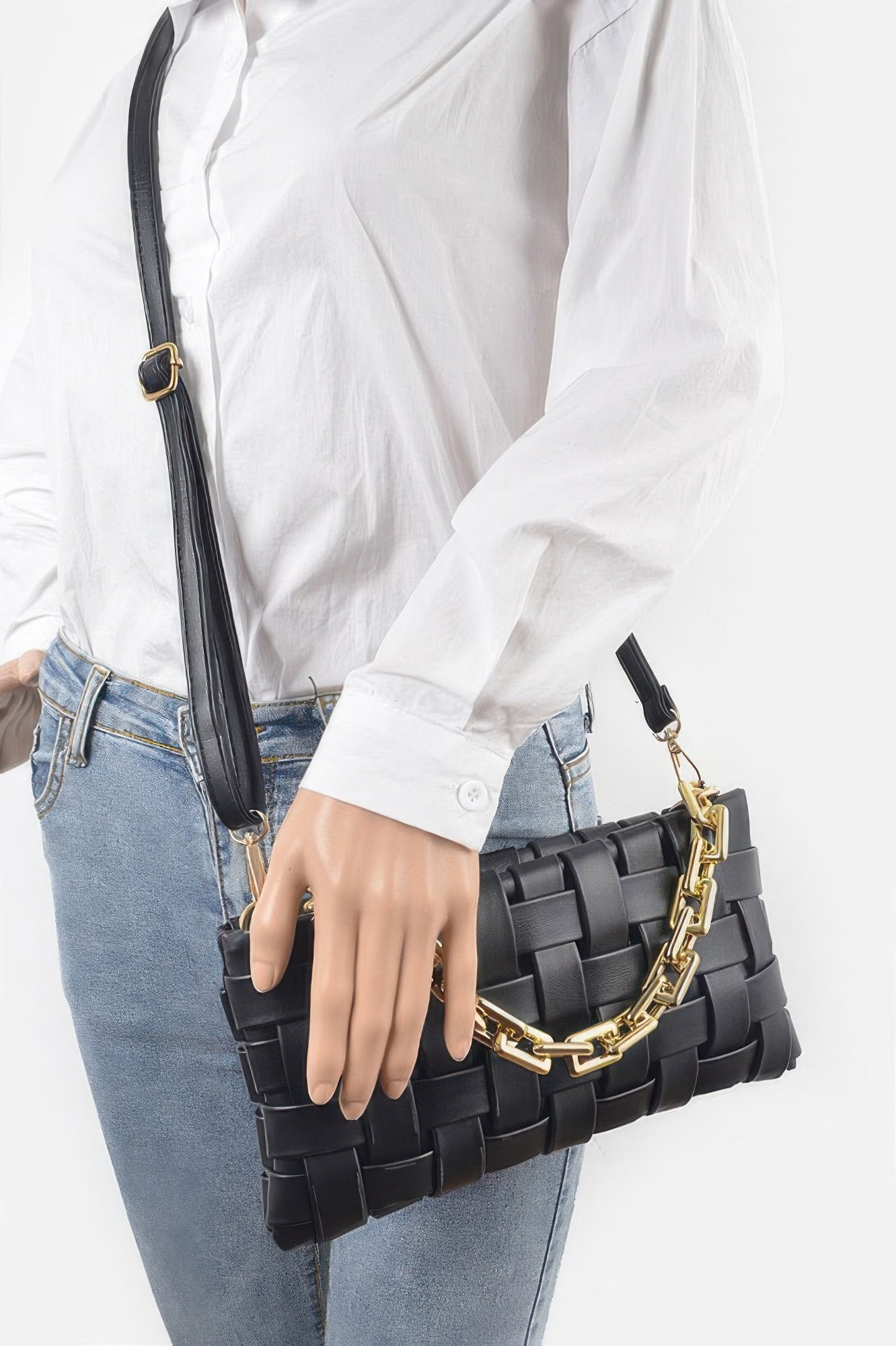 Black braided chain crossbody bag with gold chain strap, worn at the side