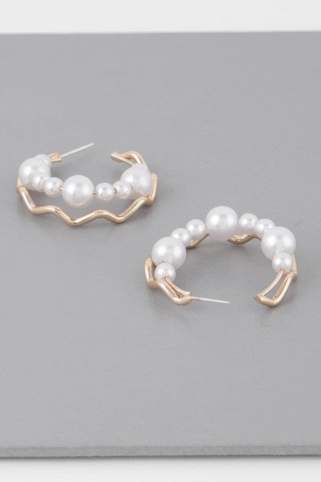 Pair of gold-cream zigzag hoop earrings with white faux pearls across the hoop