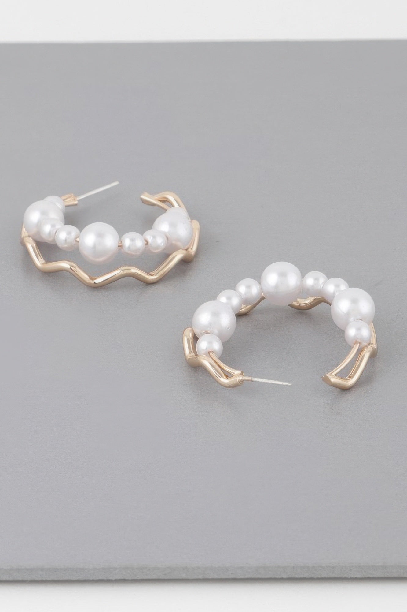 Pair of gold-cream zigzag hoop earrings with white faux pearls across the hoop