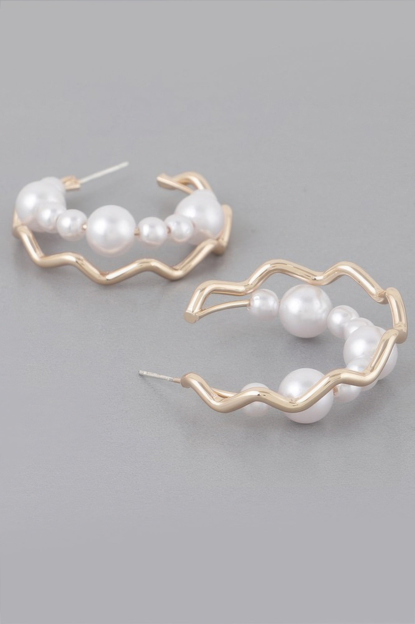 Close view of gold-cream zigzag faux pearl hoops with white faux pearls