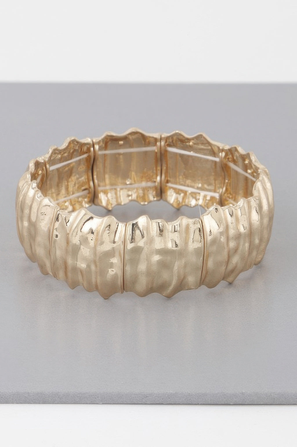 Hammered metal bracelet bangle with ridged texture and hinged interior, gold-tone