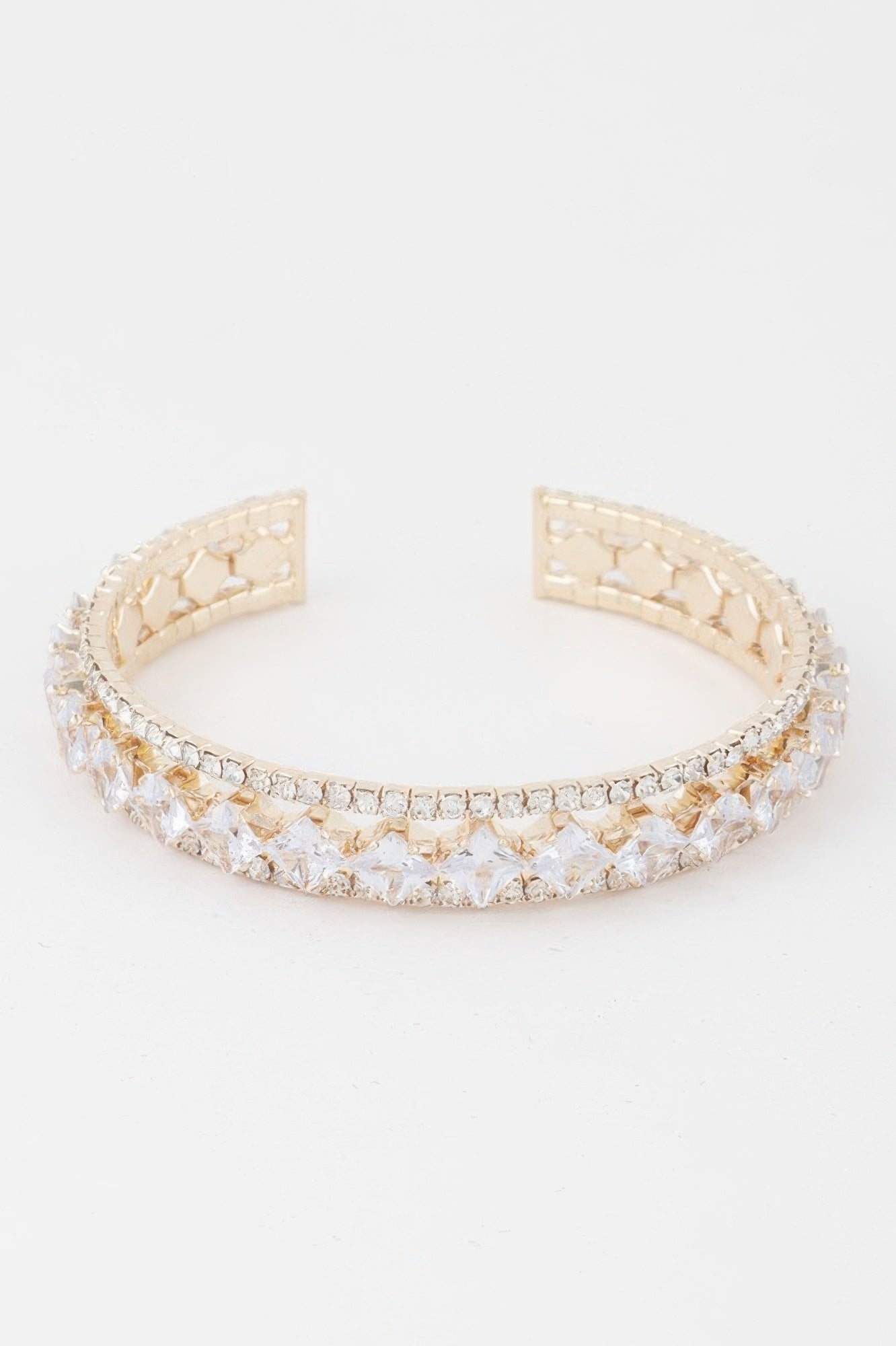 Gold-tone cubic rhinestone cuff bracelet with clear stones and hinged open ends.