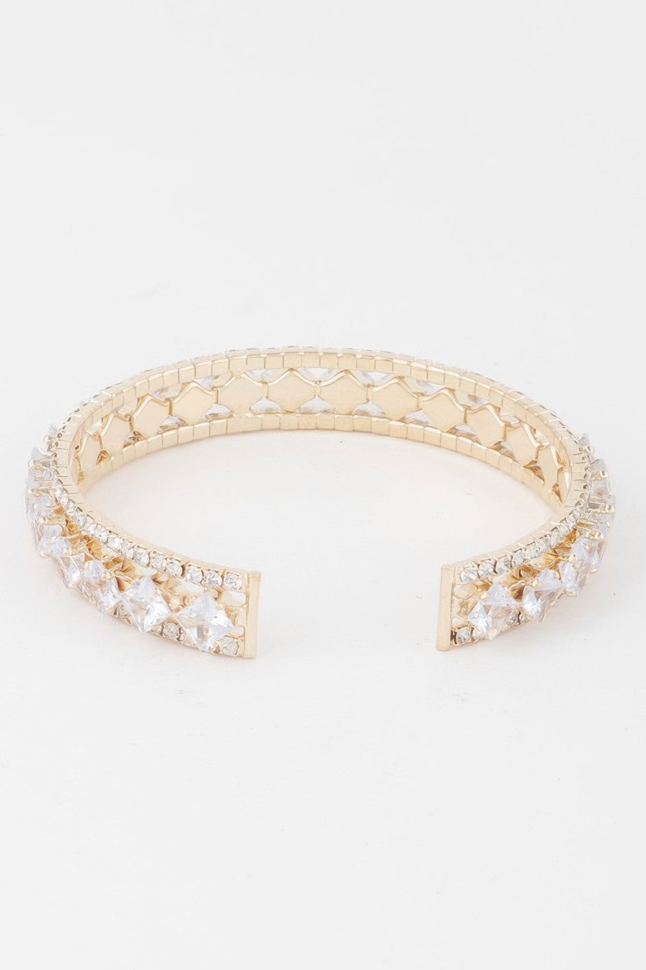 Gold-tone cubic rhinestone cuff bracelet with open clasp ends and clear stone band.