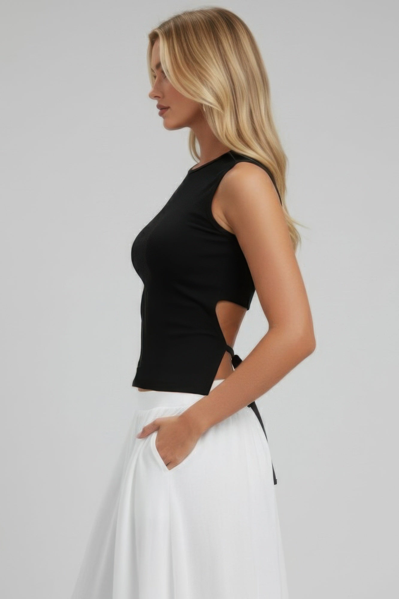 Black sleeveless mock neck top, side view with adjustable side tie at hem