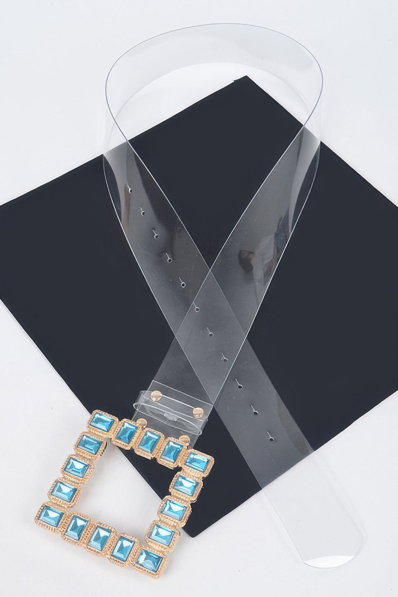 Stone buckle faux leather belt with blue square stones on clear strap, side view