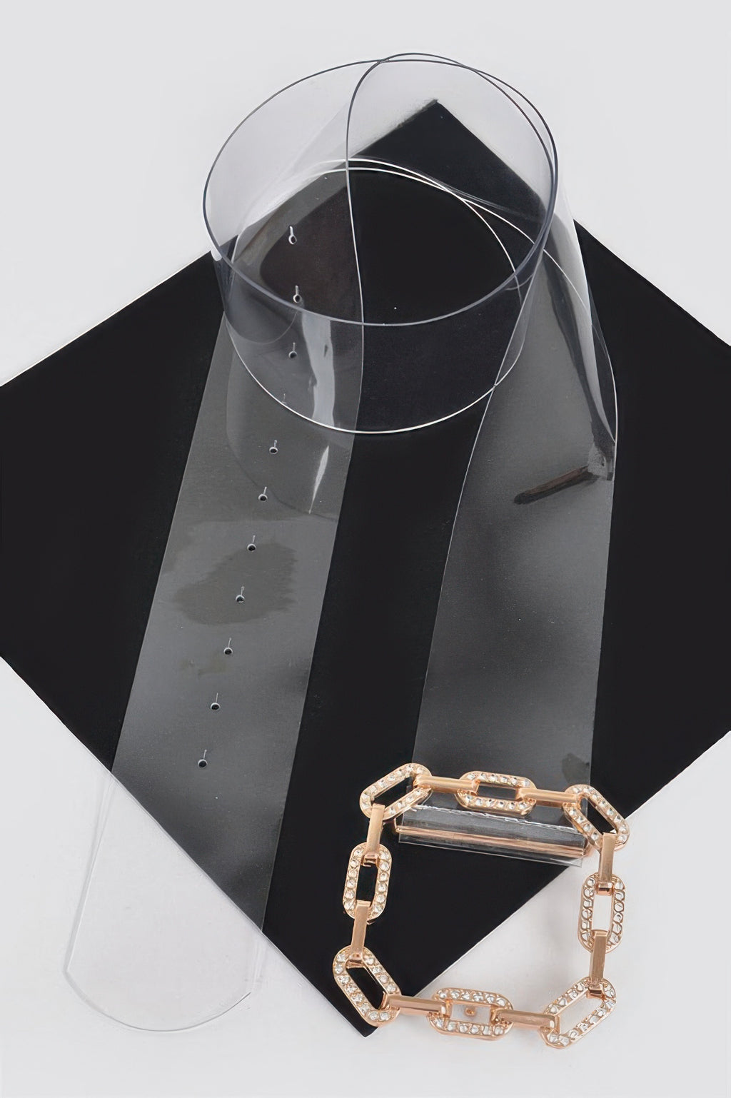 Gold chain-link rhinestone buckle on clear transparent belt, angled view