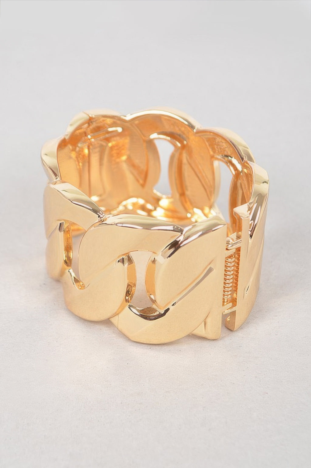 Gold wide chain bracelet featuring textured, faceted metal links and open cuff fit