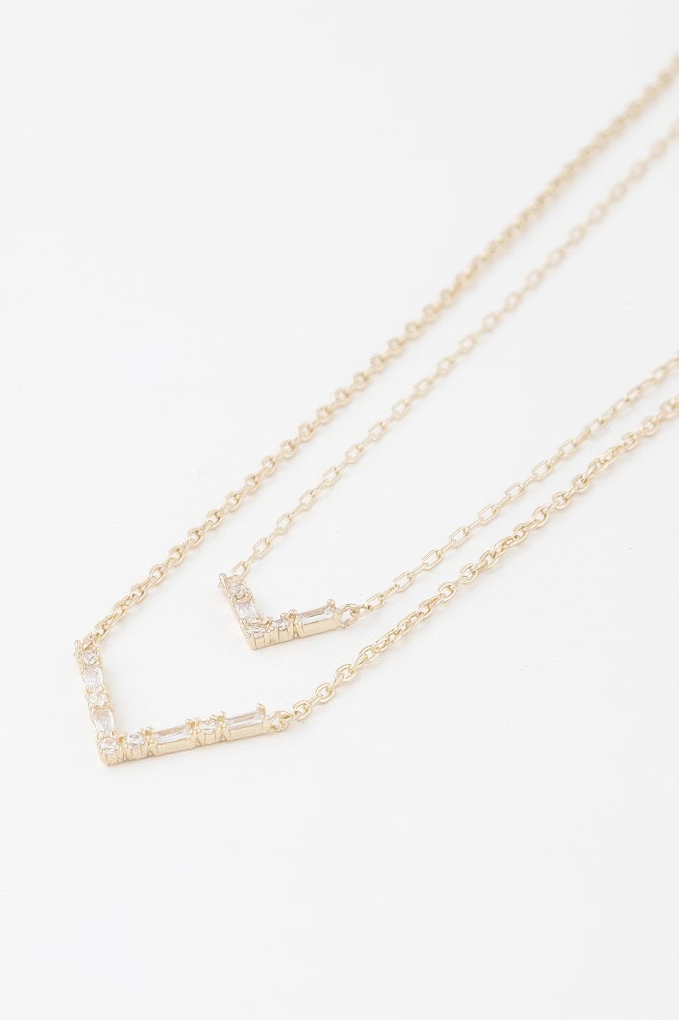 Gold-tone double V crystal necklace close-up showing two rectangular crystal settings