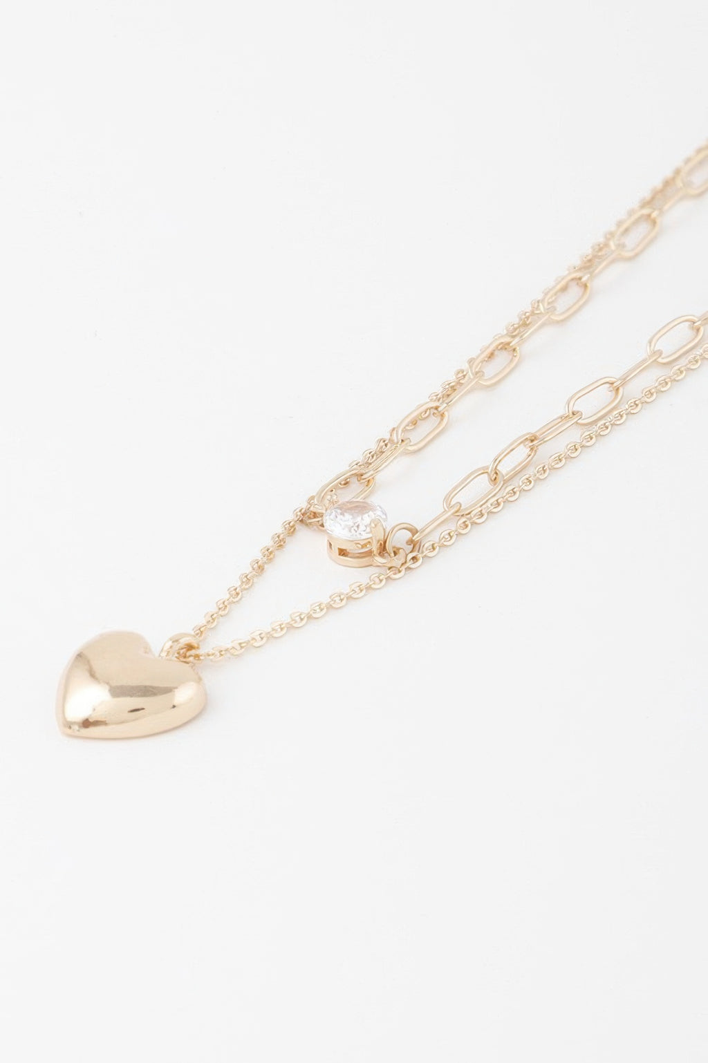 Close-up gold heart pendant necklace with small clear-stone heart charm on chain