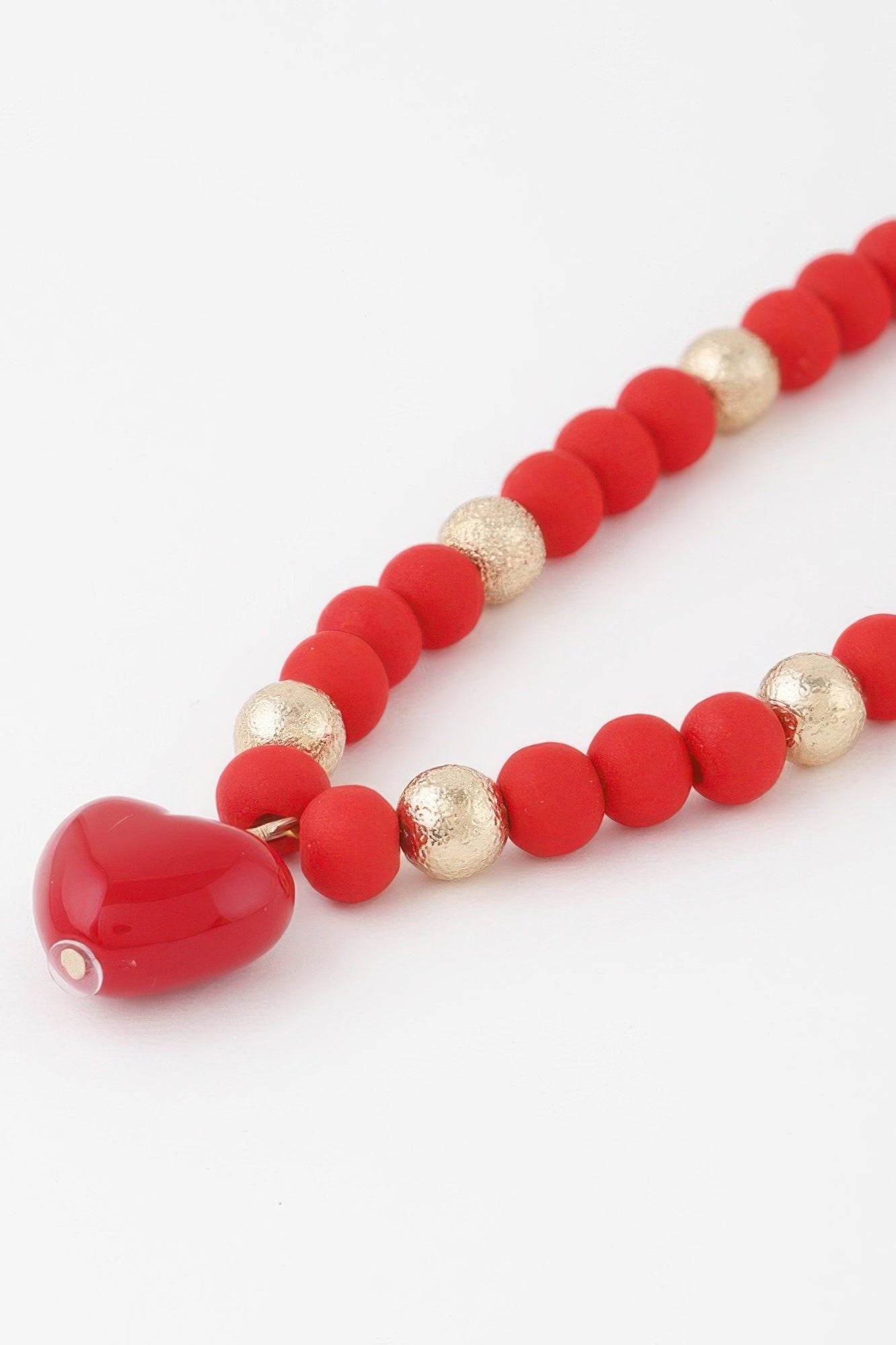 Close-up of red heart beaded necklace with gold beads and heart drop pendant