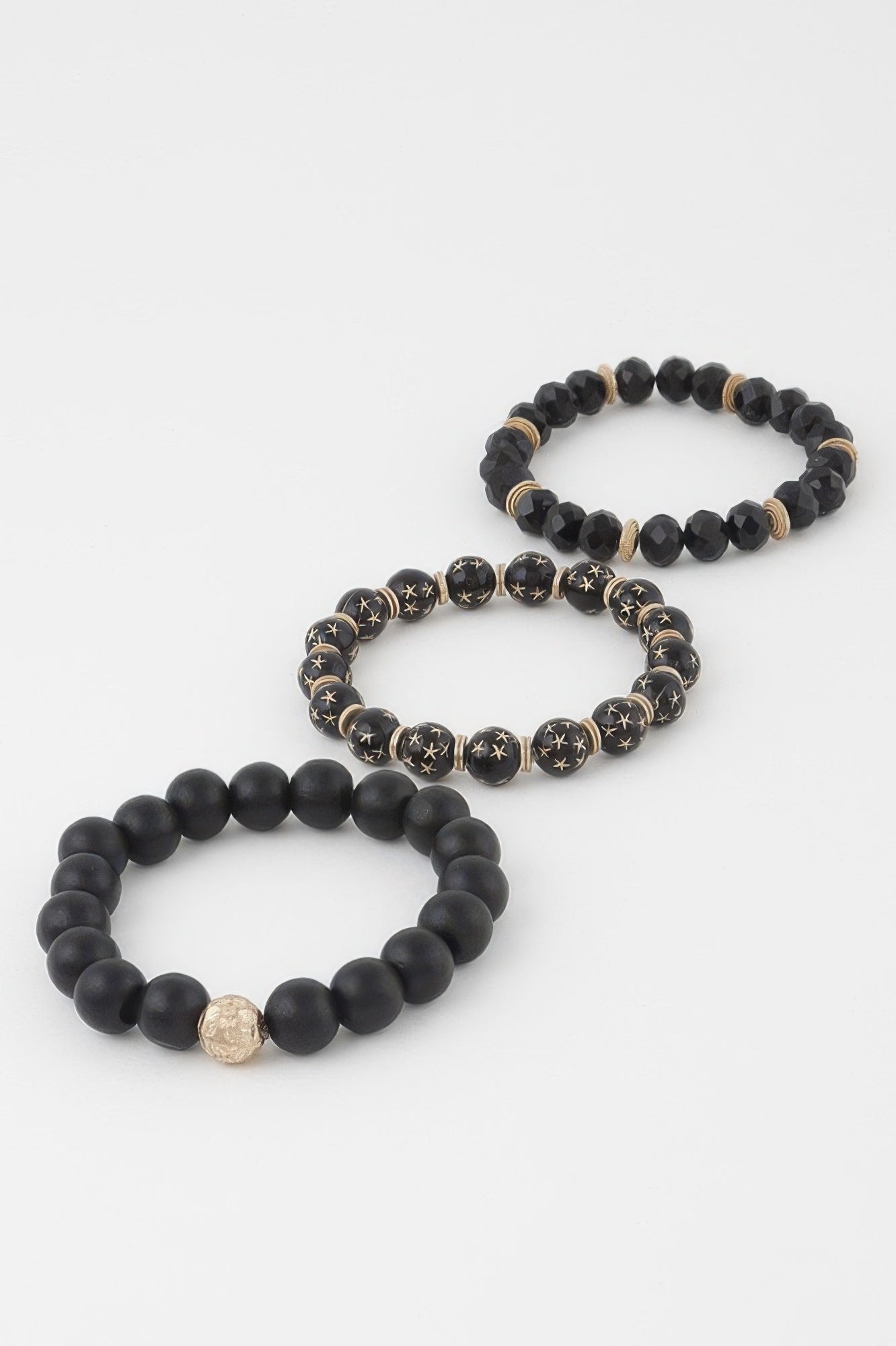 Three-layer bracelet in black: round beads, star discs, and small gold charm