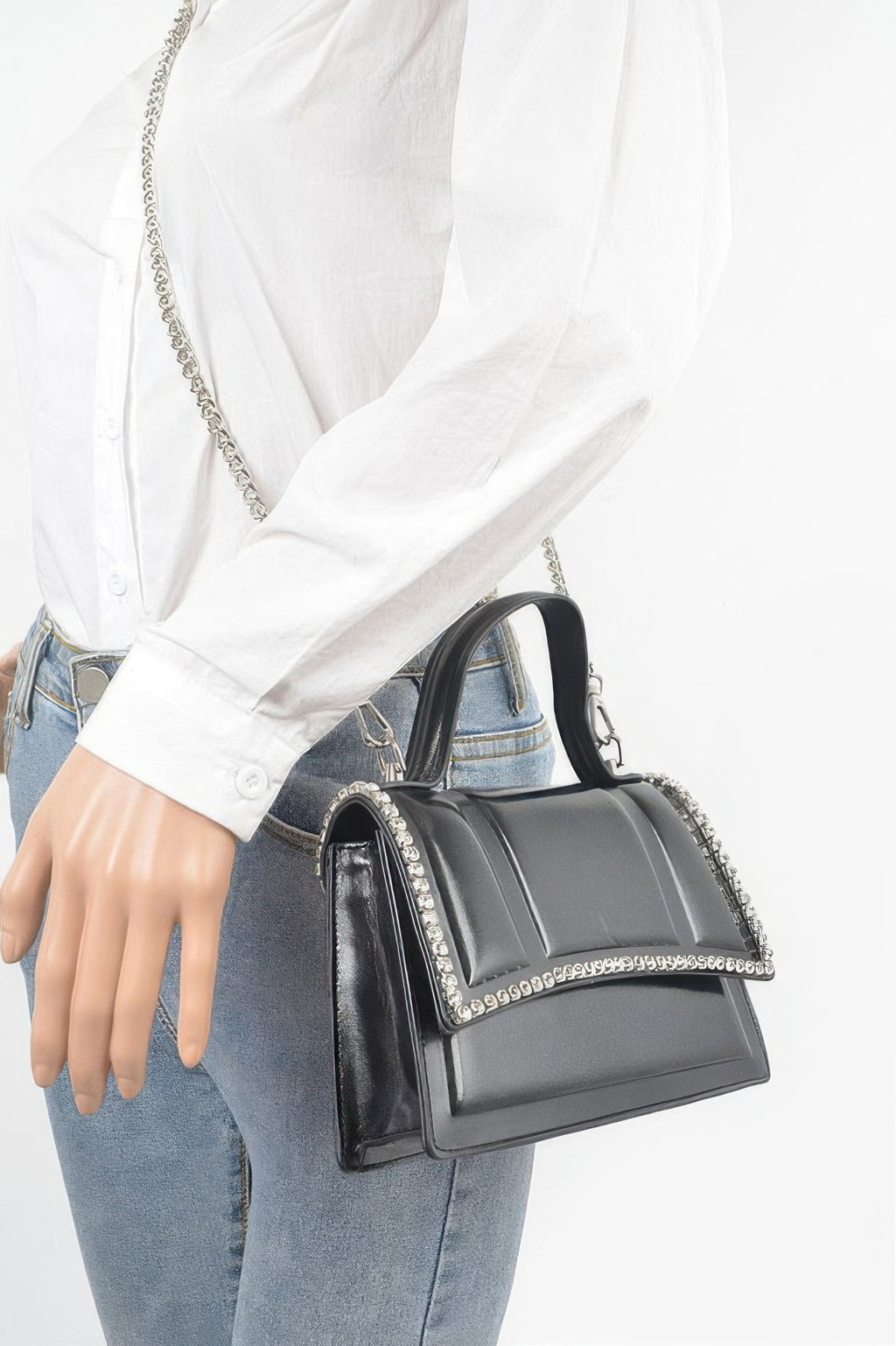 Black metallic top-handle bag worn on shoulder with rhinestone trim and chain strap