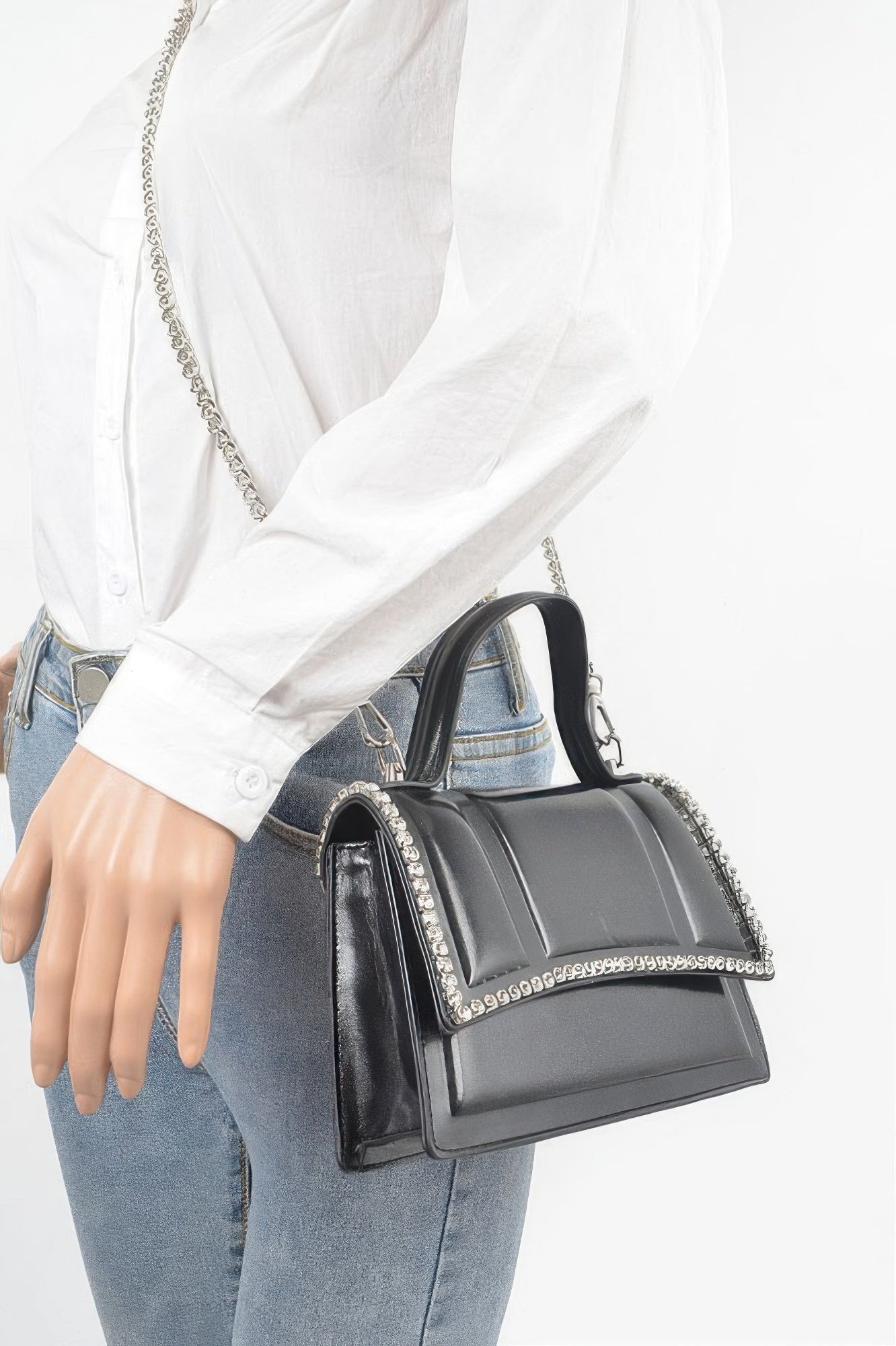 Black metallic top-handle bag worn on shoulder with rhinestone trim and chain strap