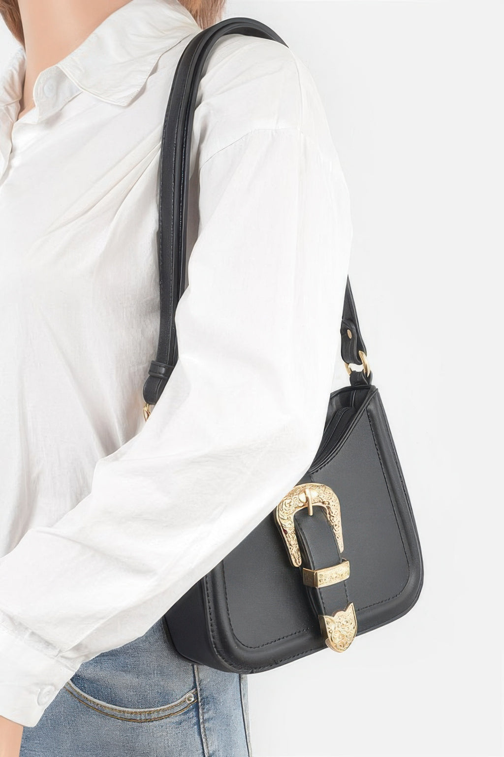 Black vegan shoulder bag worn at side; gold-tone metal buckle and curved top