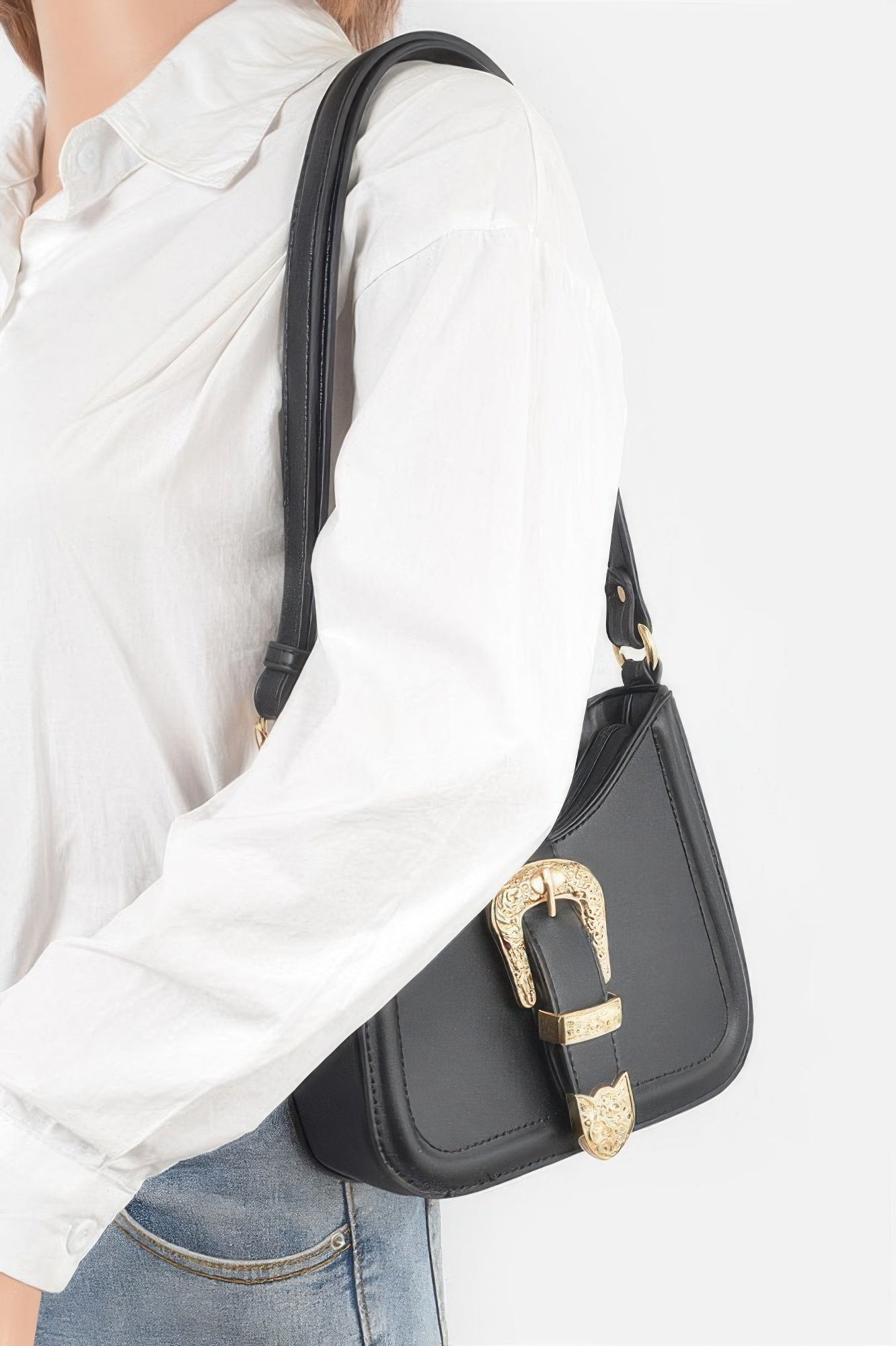 Black vegan shoulder bag worn at side; gold-tone metal buckle and curved top