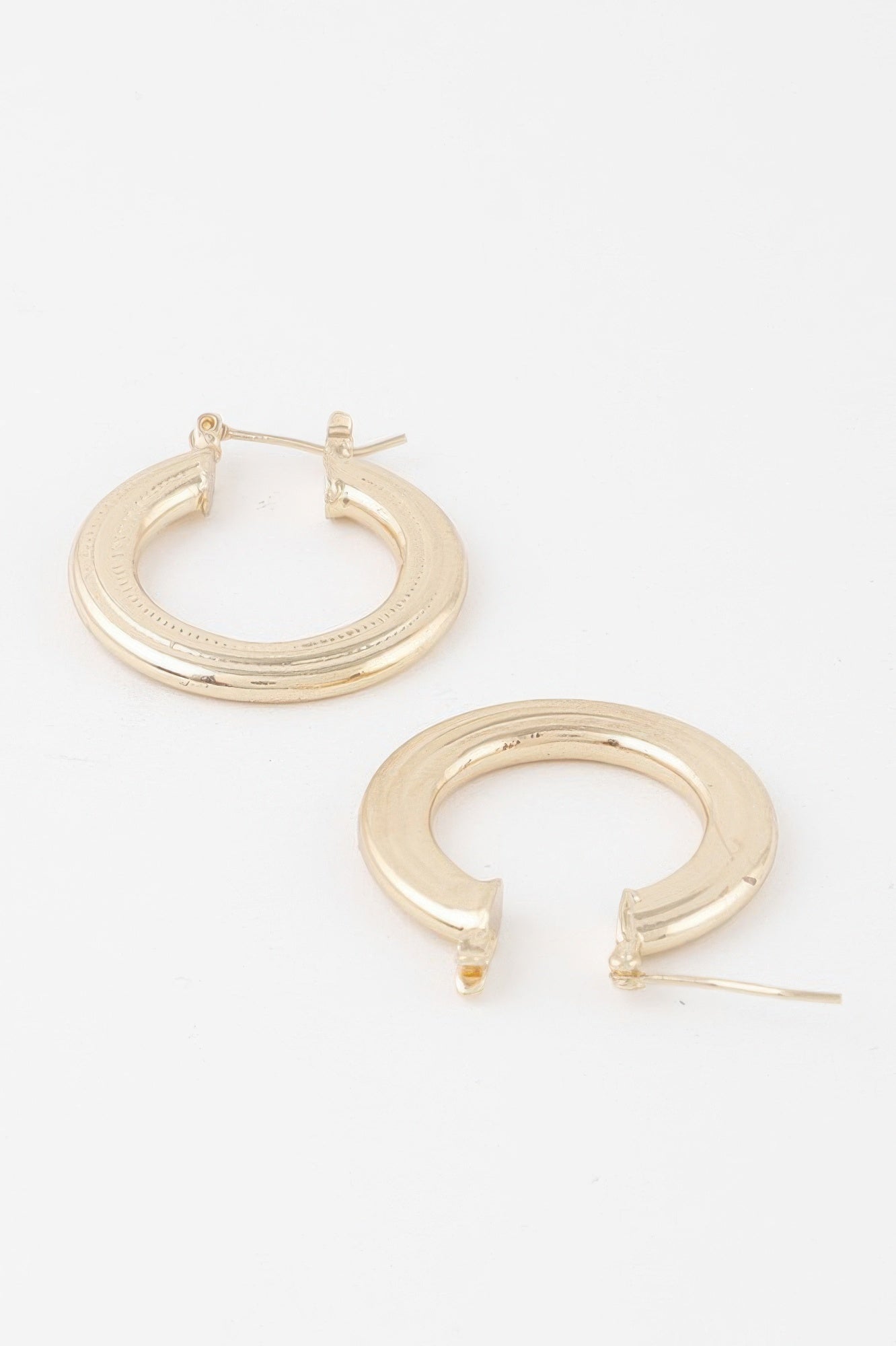 Gold minimal flat hoop earrings with circular hoop shape and small hinge detail