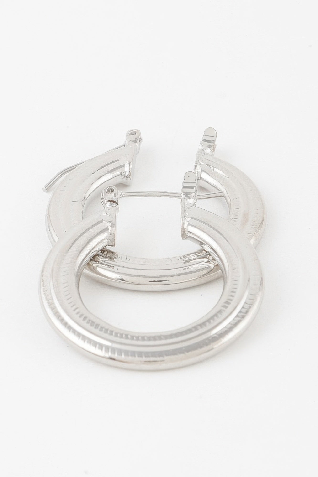 Minimal flat hoop earrings in silver, textured outer ring with hinged posts