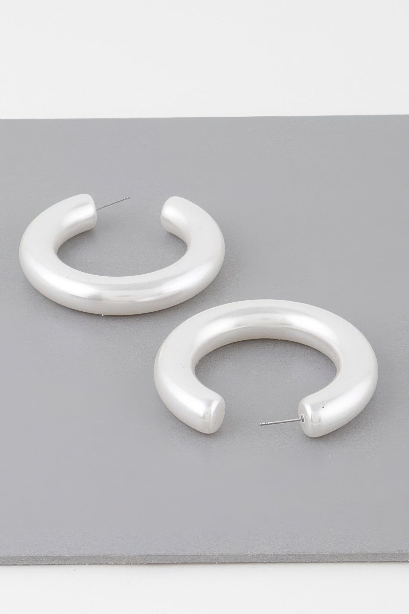 Polished cream hoop earrings with visible stud post, glossy finish