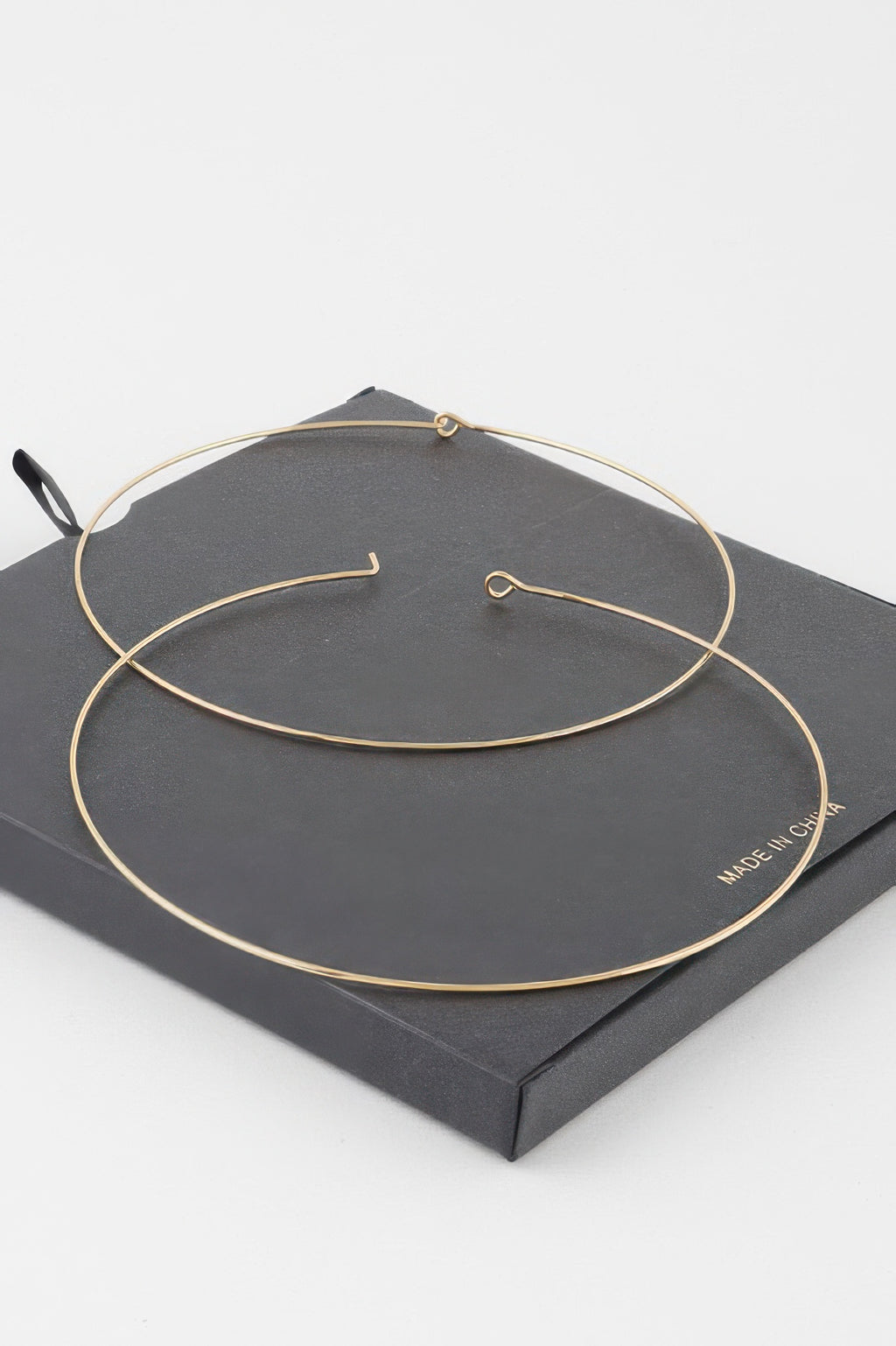 Gold wide flat hoop earrings with simple hook closures on display