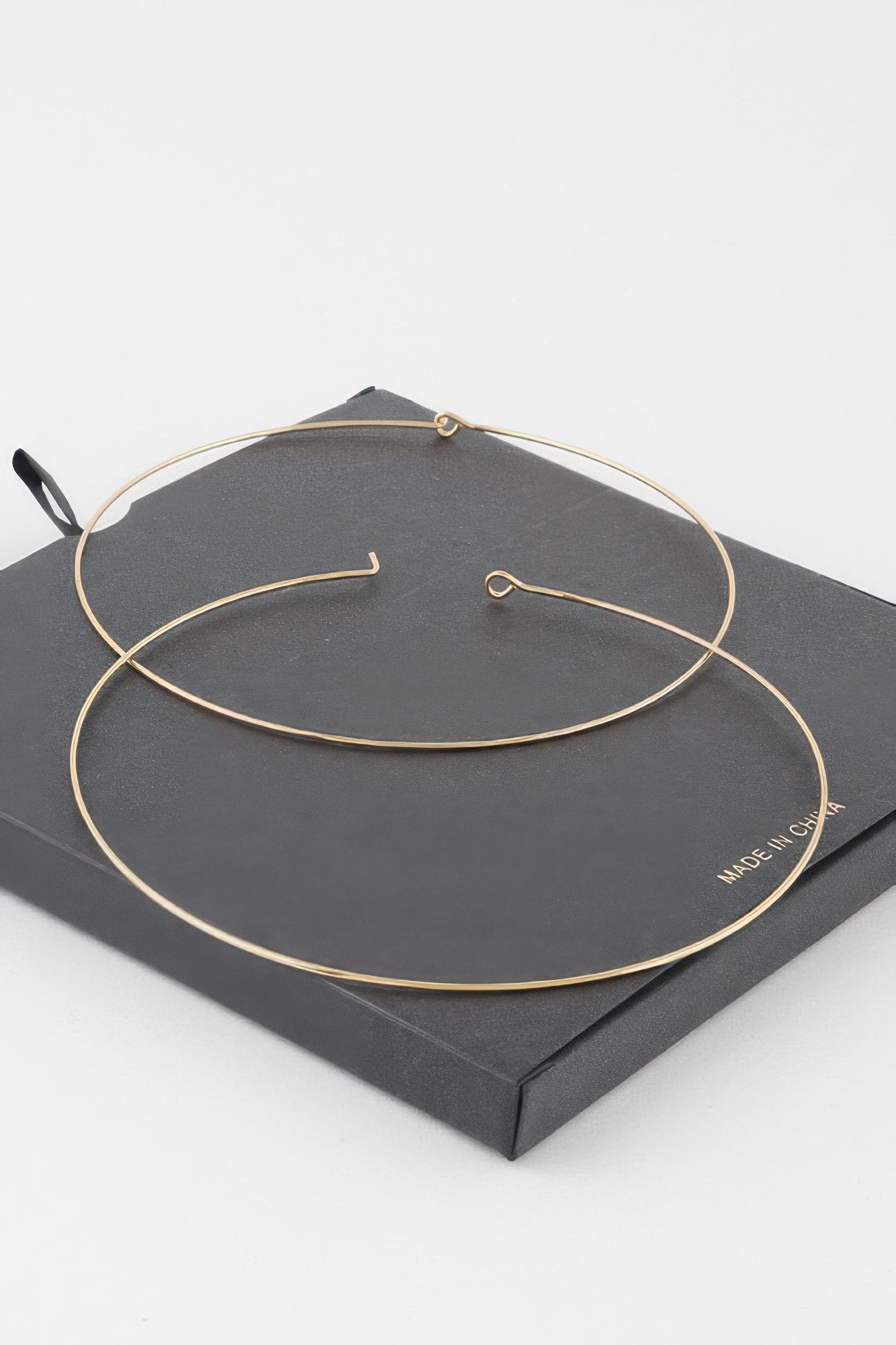 Gold wide flat hoop earrings with simple hook closures on display