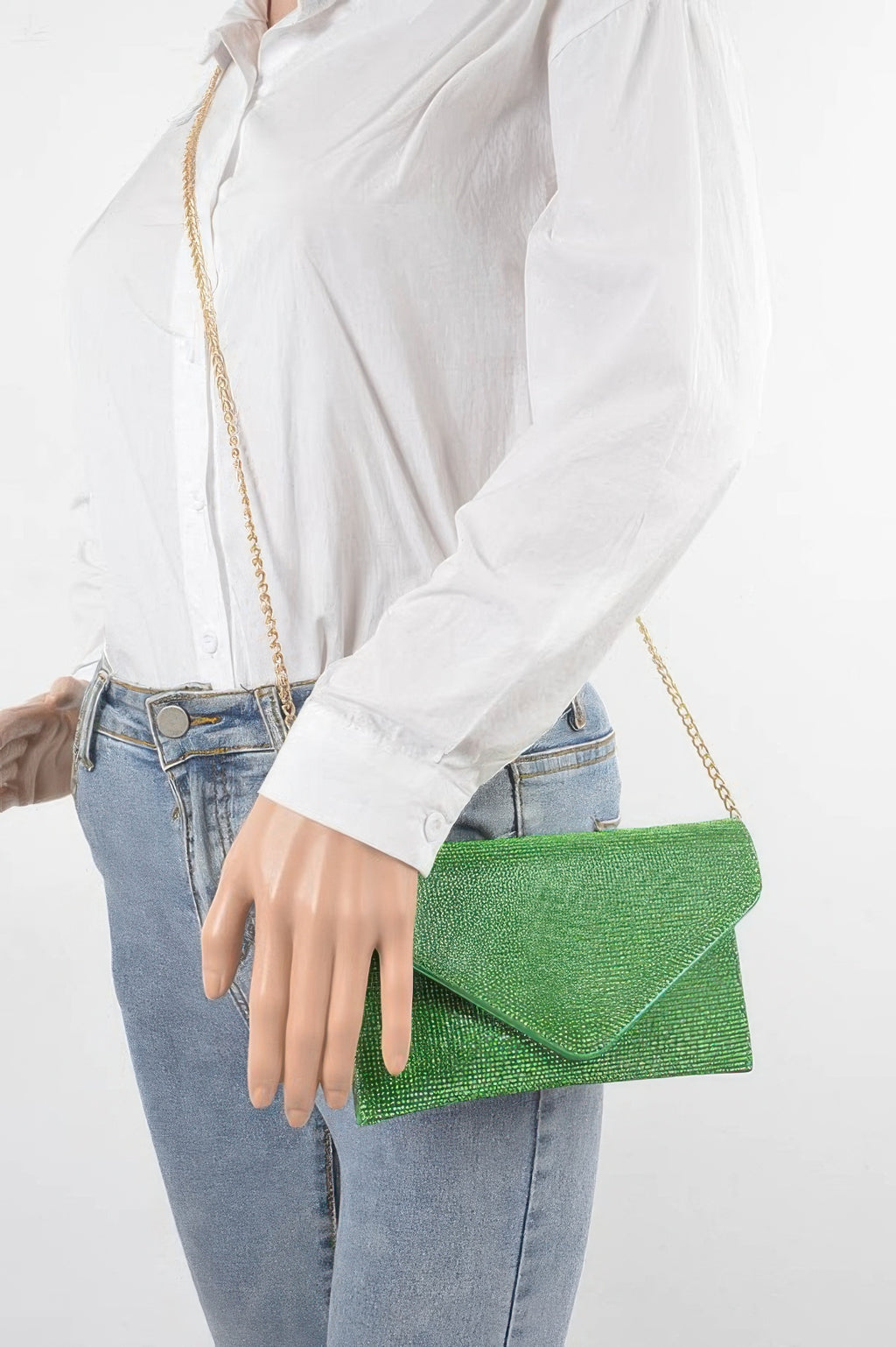 Model holding green rhinestone envelope clutch with gold chain