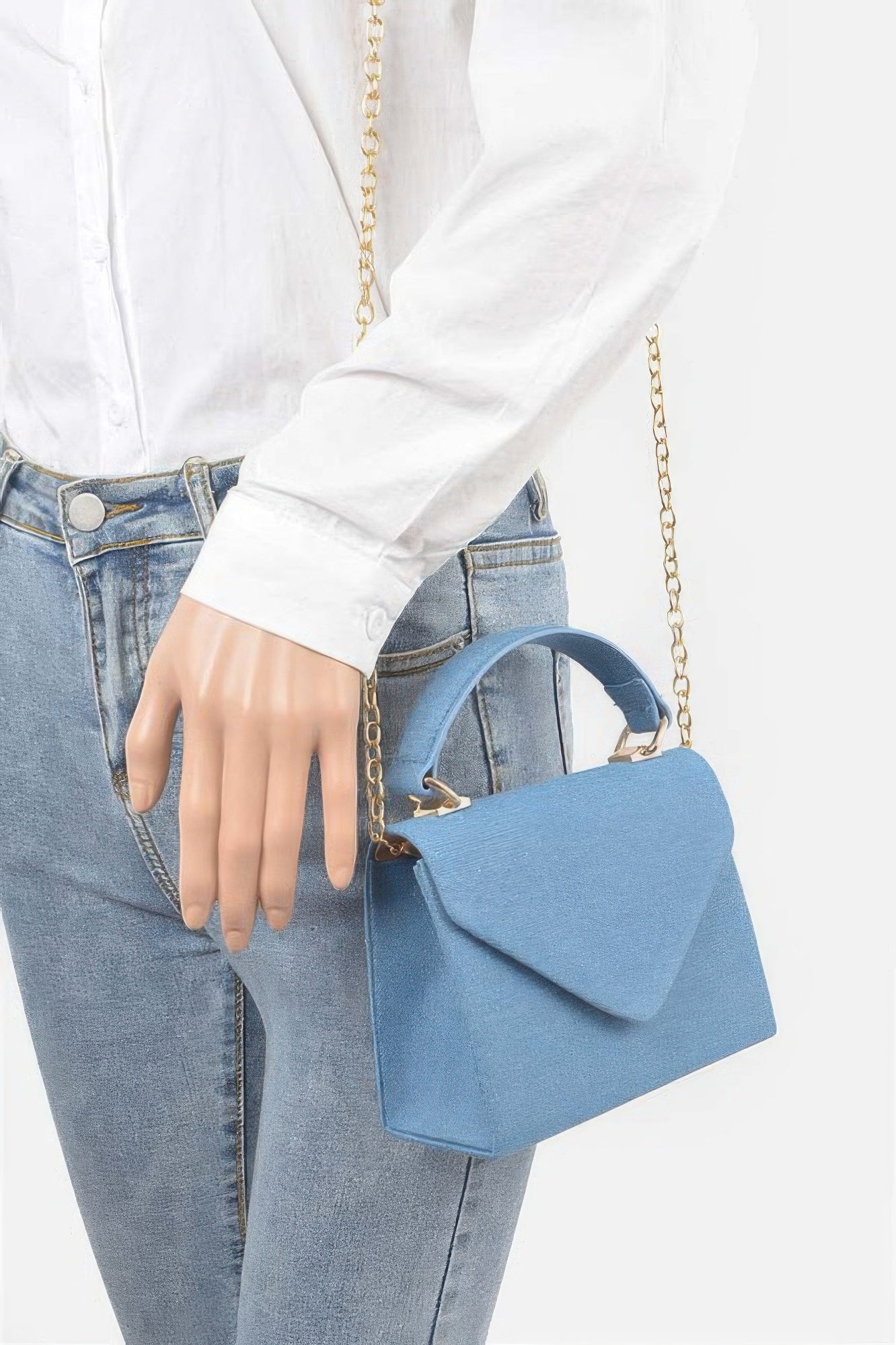 Bolso bandolera cruzado denim azul claro, con cadena dorada, usado sobre el hombro