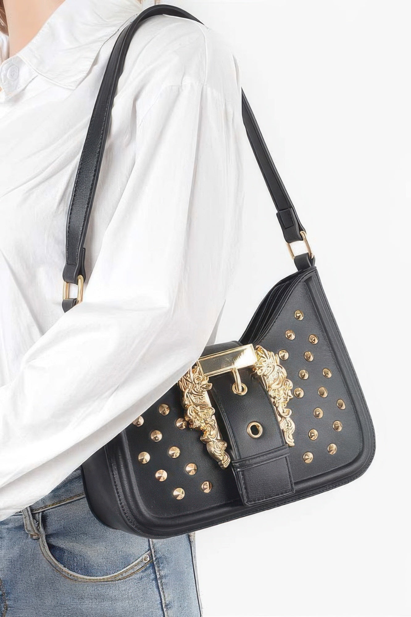 Black studded faux leather shoulder bag worn with long strap and gold-tone buckle centerpiece