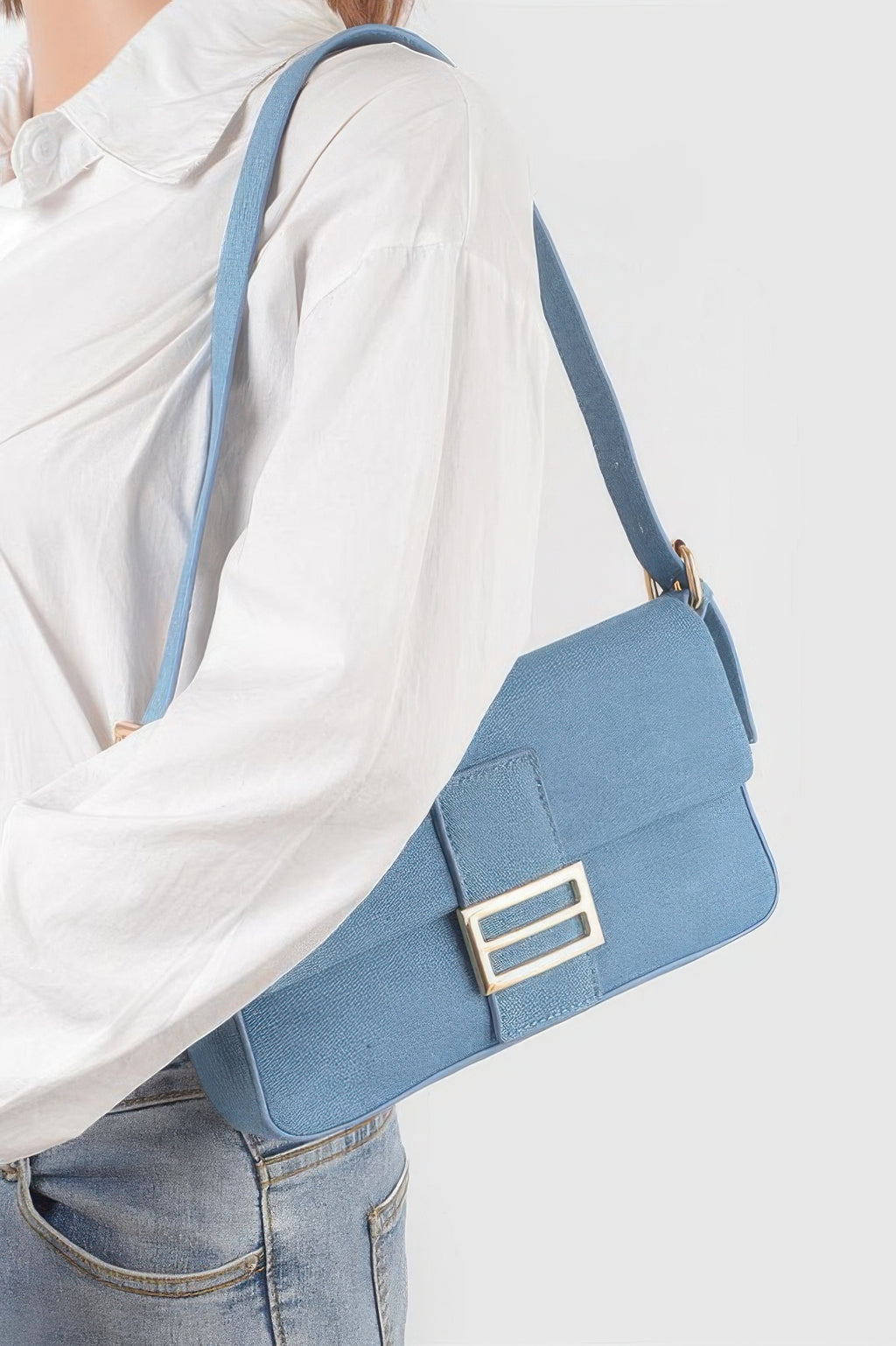 Light blue denim shoulder bag worn on model, gold-tone buckle on front flap