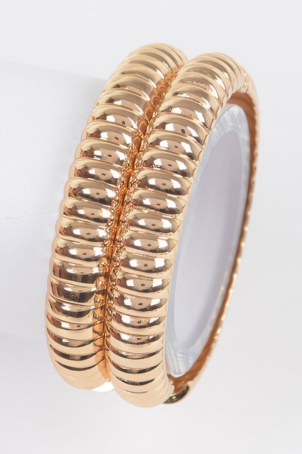 Gold two-piece metal bangle set, ribbed oval bangles with smooth hinged clasp.
