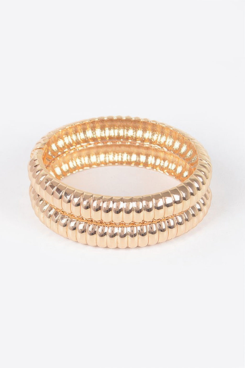 Gold ribbed oval bangles stacked look, polished metal with scalloped edge details.