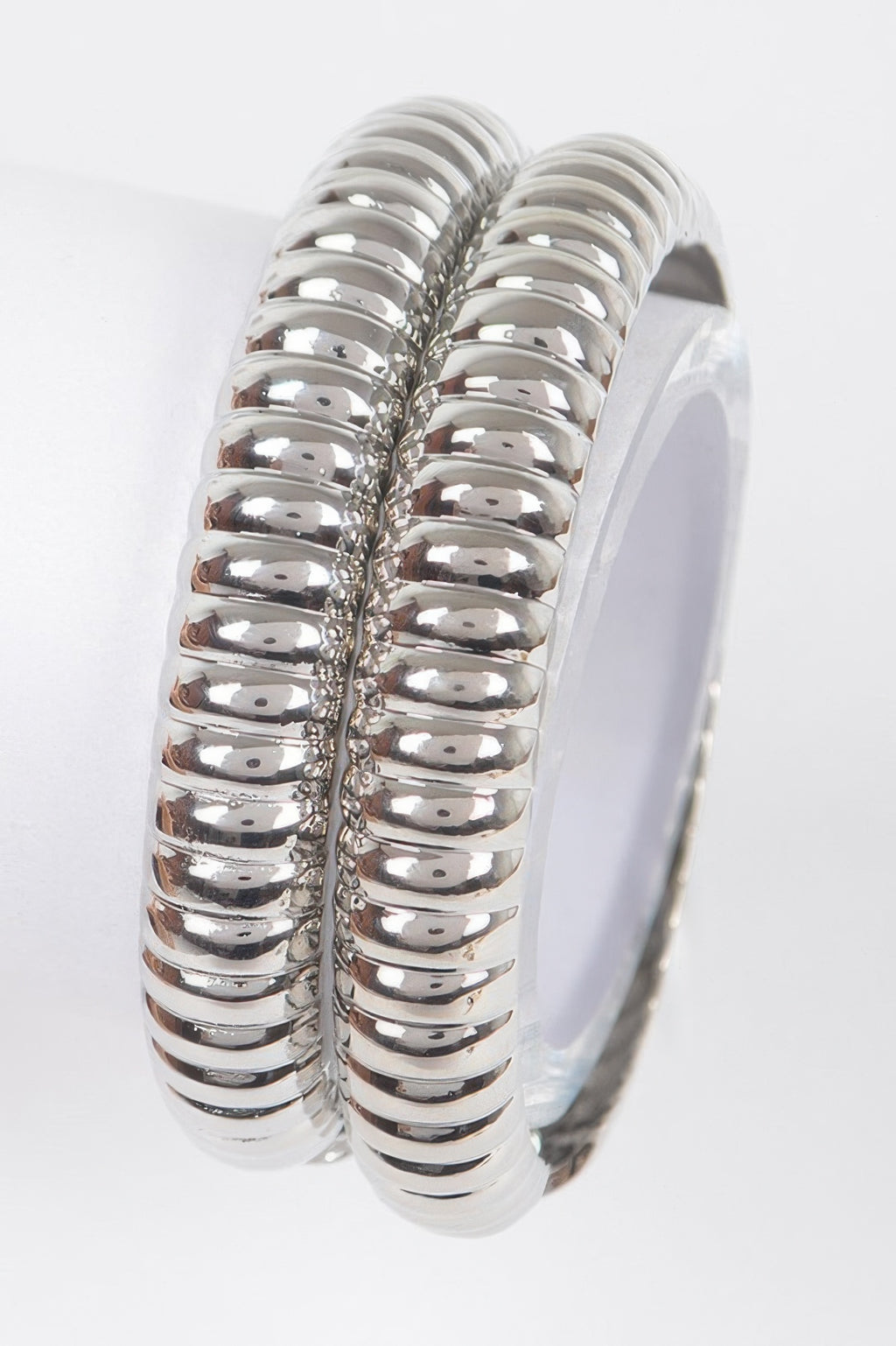Silver two-piece metal bangle set, ribbed oval hoops with hinged clasp seam.