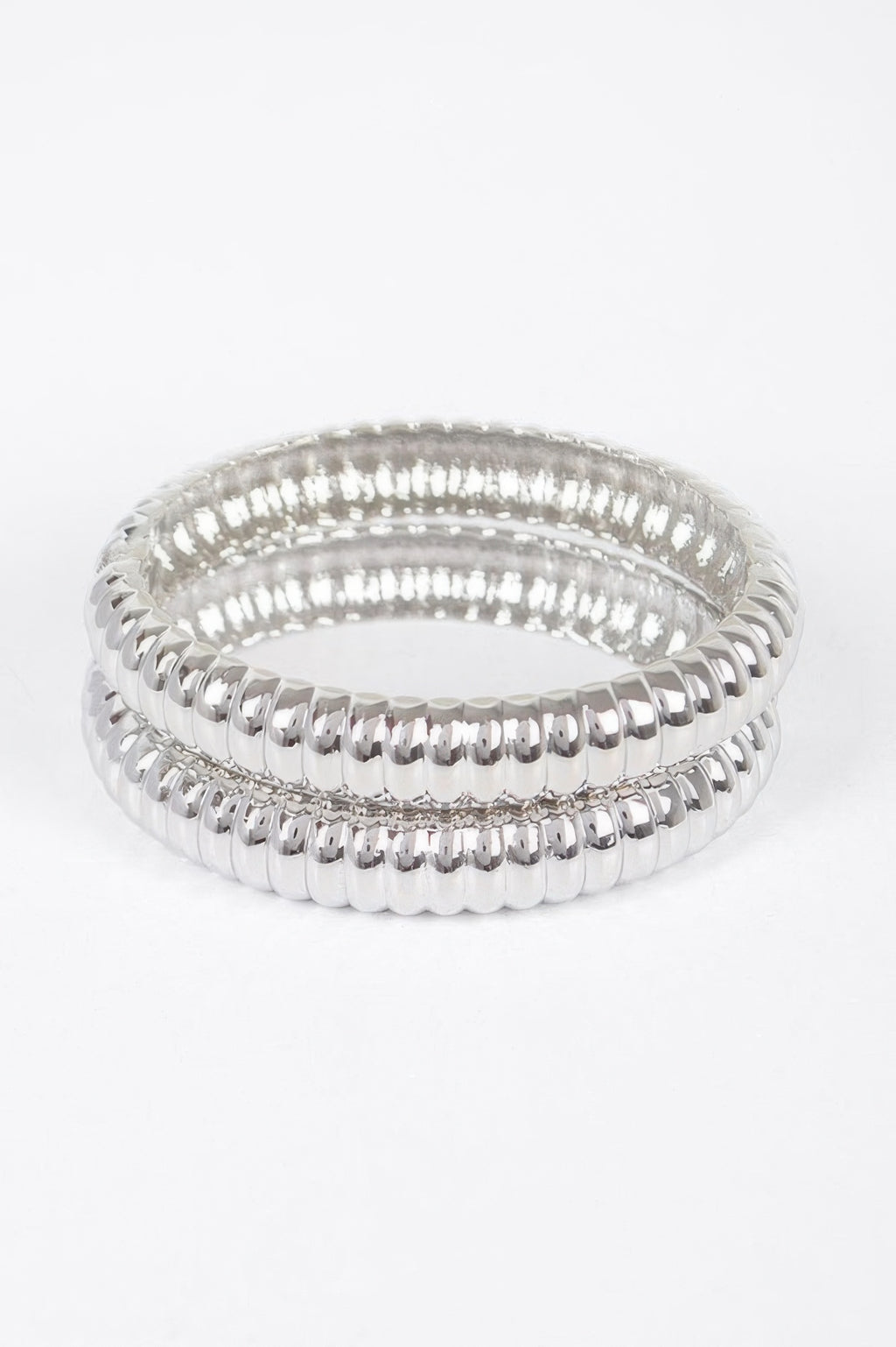 Silver ribbed oval bangles set, stacked hoops with polished reflective edge rows.