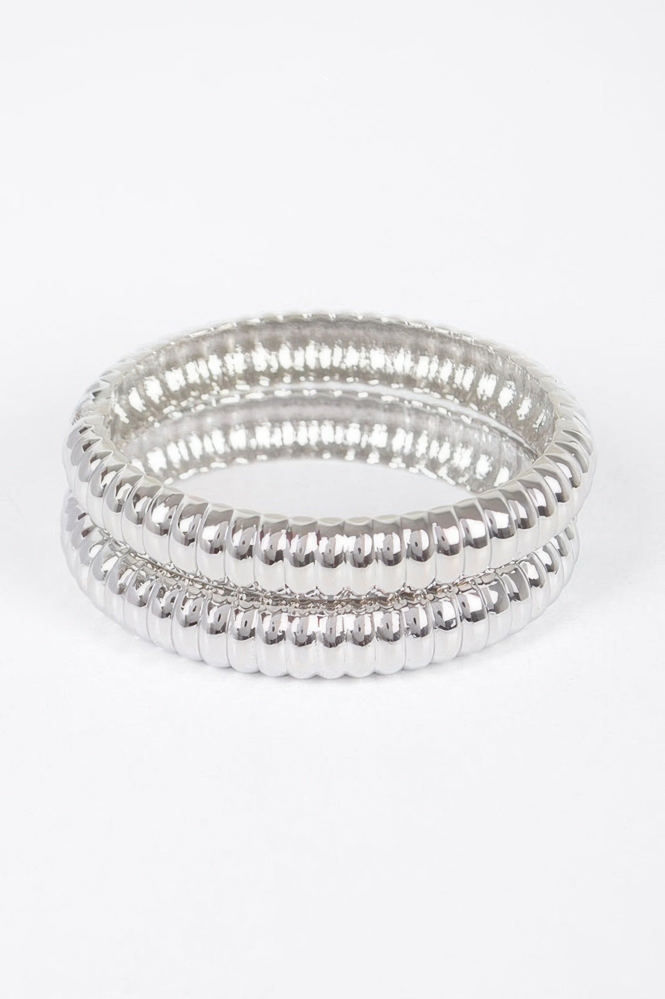 Silver ribbed oval bangles set, stacked hoops with polished reflective edge rows.