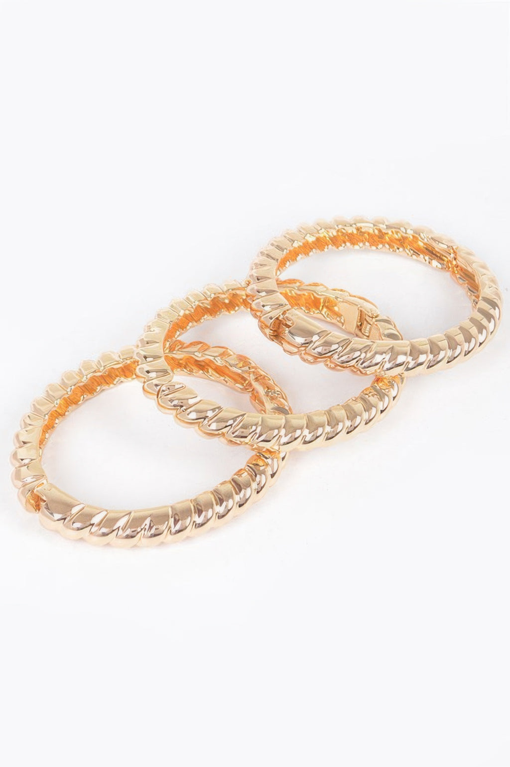 Three-piece metal bangle set, gold-tone linked bangles stacked in a side view