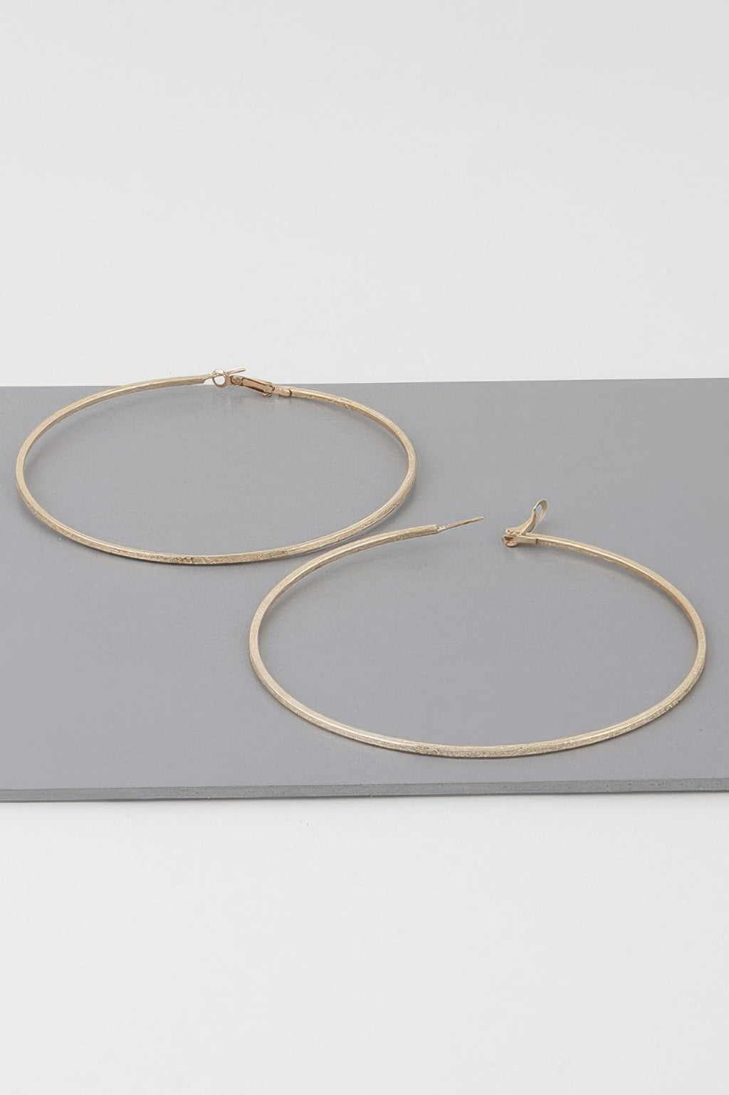 Wide indented hoop earrings, gold tone; large circular hoops with clasp details