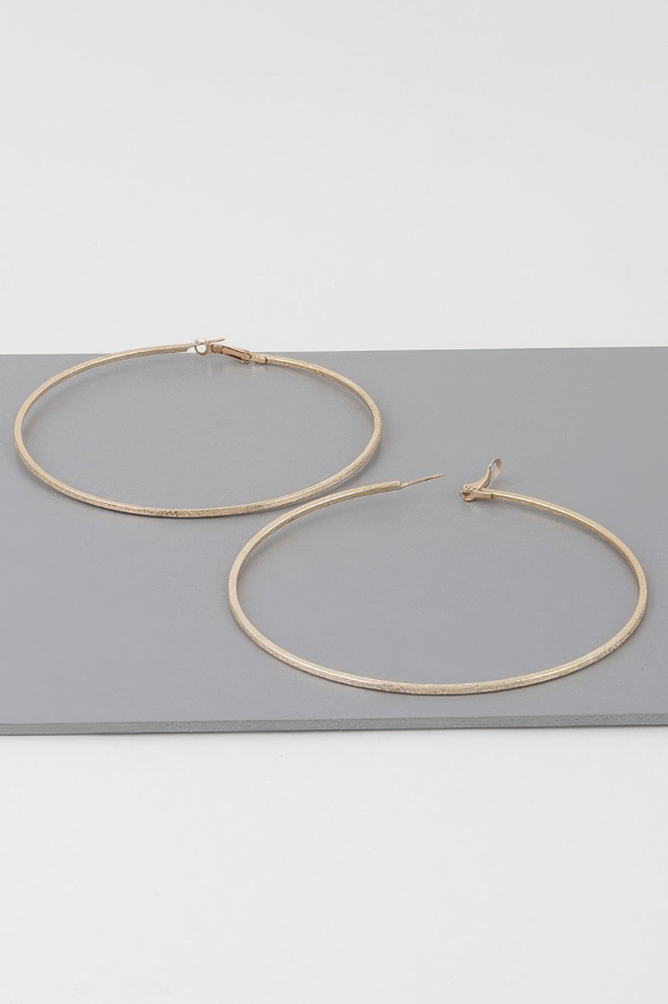 Wide indented hoop earrings, gold tone; large circular hoops with clasp details