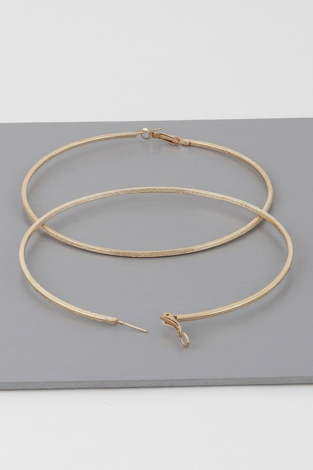 Wide indented hoop earrings, gold tone; overlapping hoops with subtle textured ridges