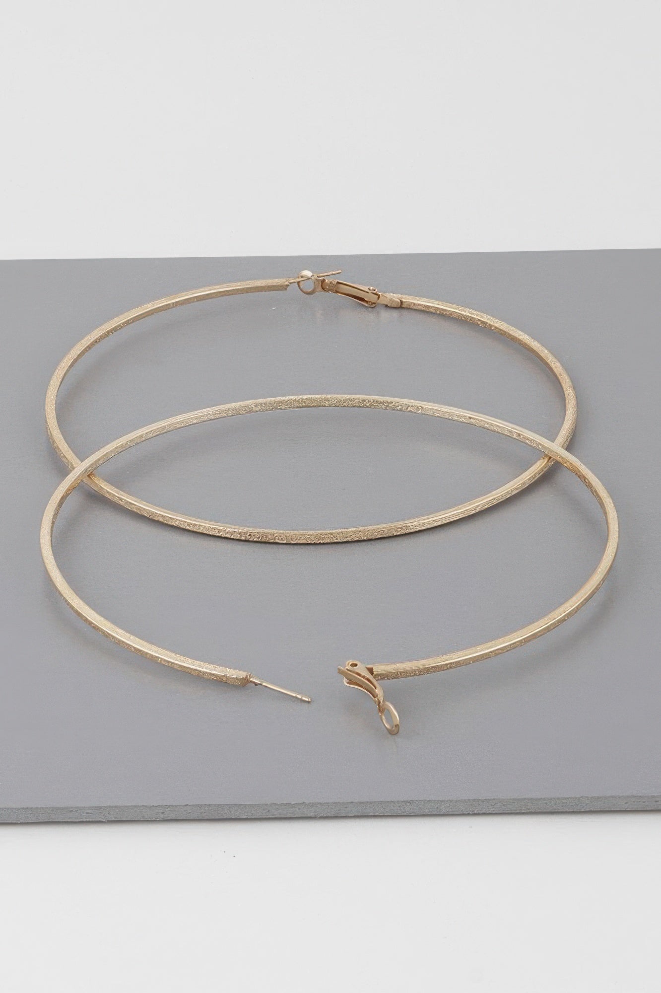 Wide indented hoop earrings, gold tone; overlapping hoops with subtle textured ridges