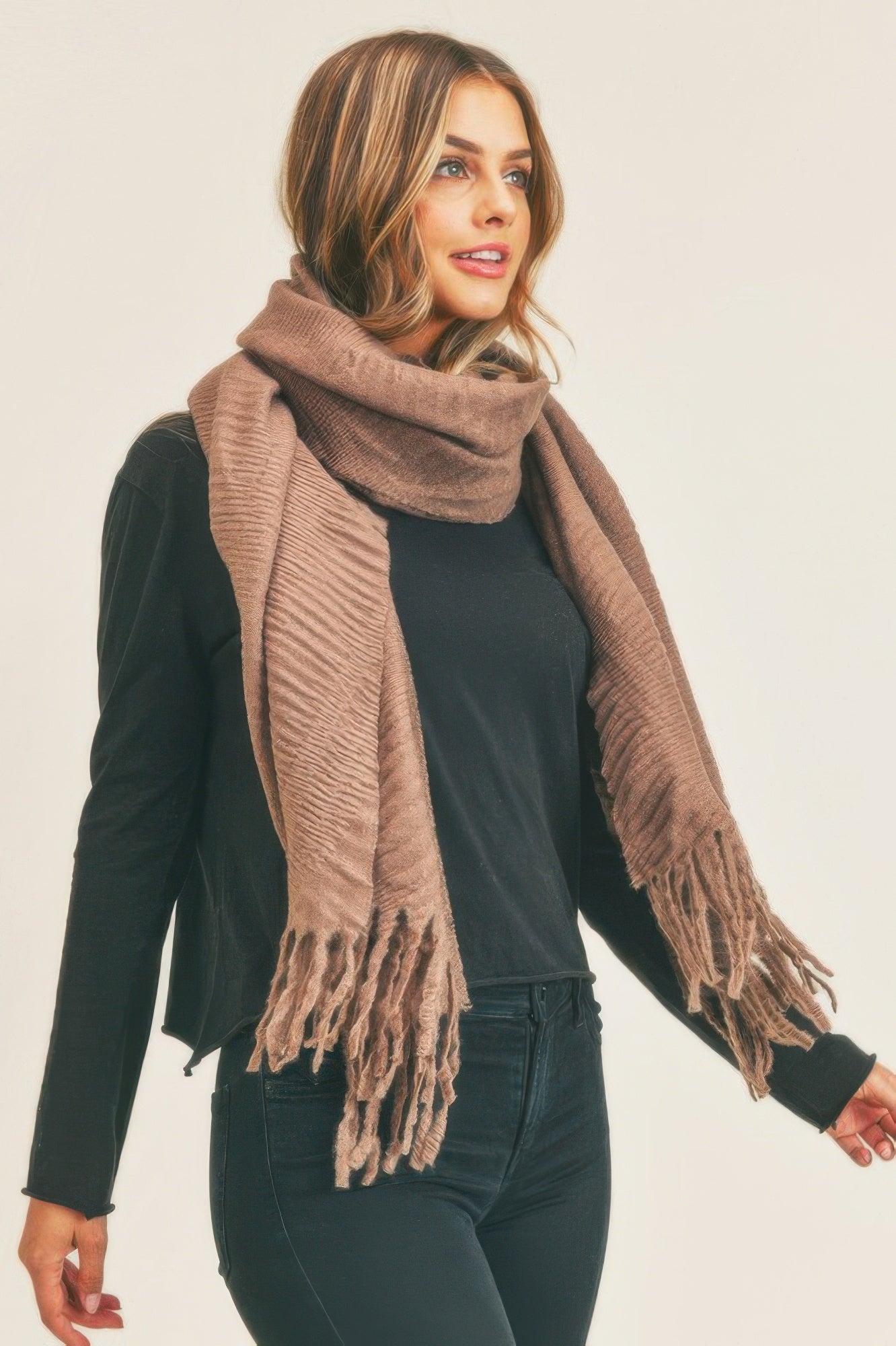 Brown pleated scarf draped over shoulder with fringed trim