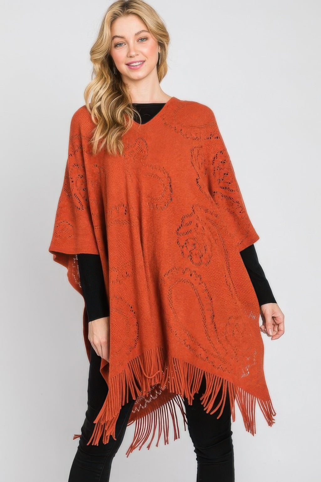 Rust paisley fringe poncho with asymmetrical drape and decorative knit pattern across front.