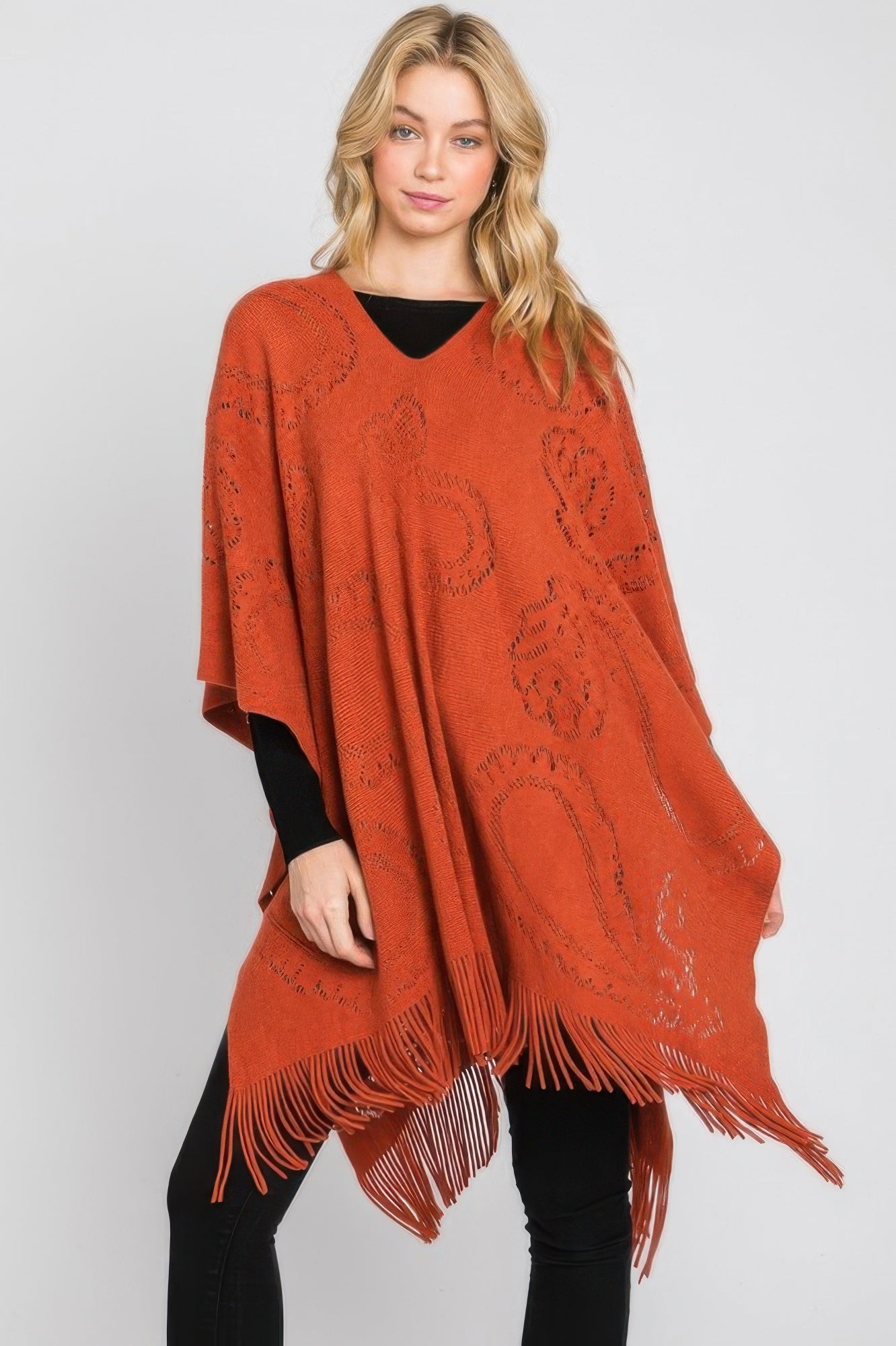 Rust orange paisley poncho, oversized draped fit with knit motifs and fringe at bottom.