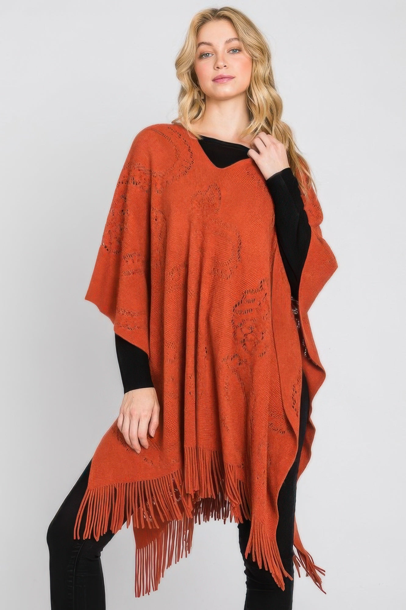 Rust orange paisley fringe poncho with relaxed drape and tassel trim at the hem.