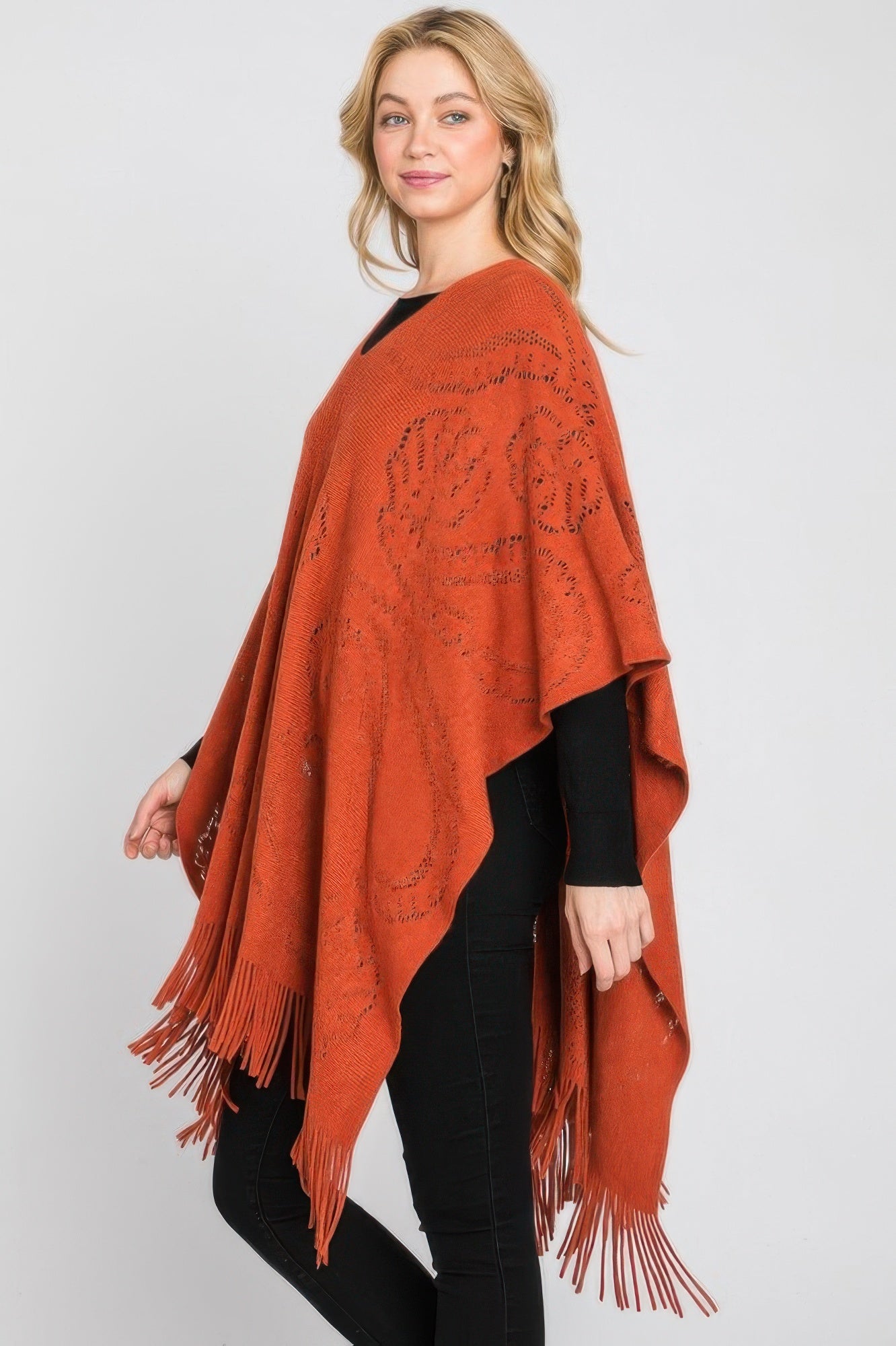 Rust orange paisley poncho, side view with fringe tassels and woven motif detailing.
