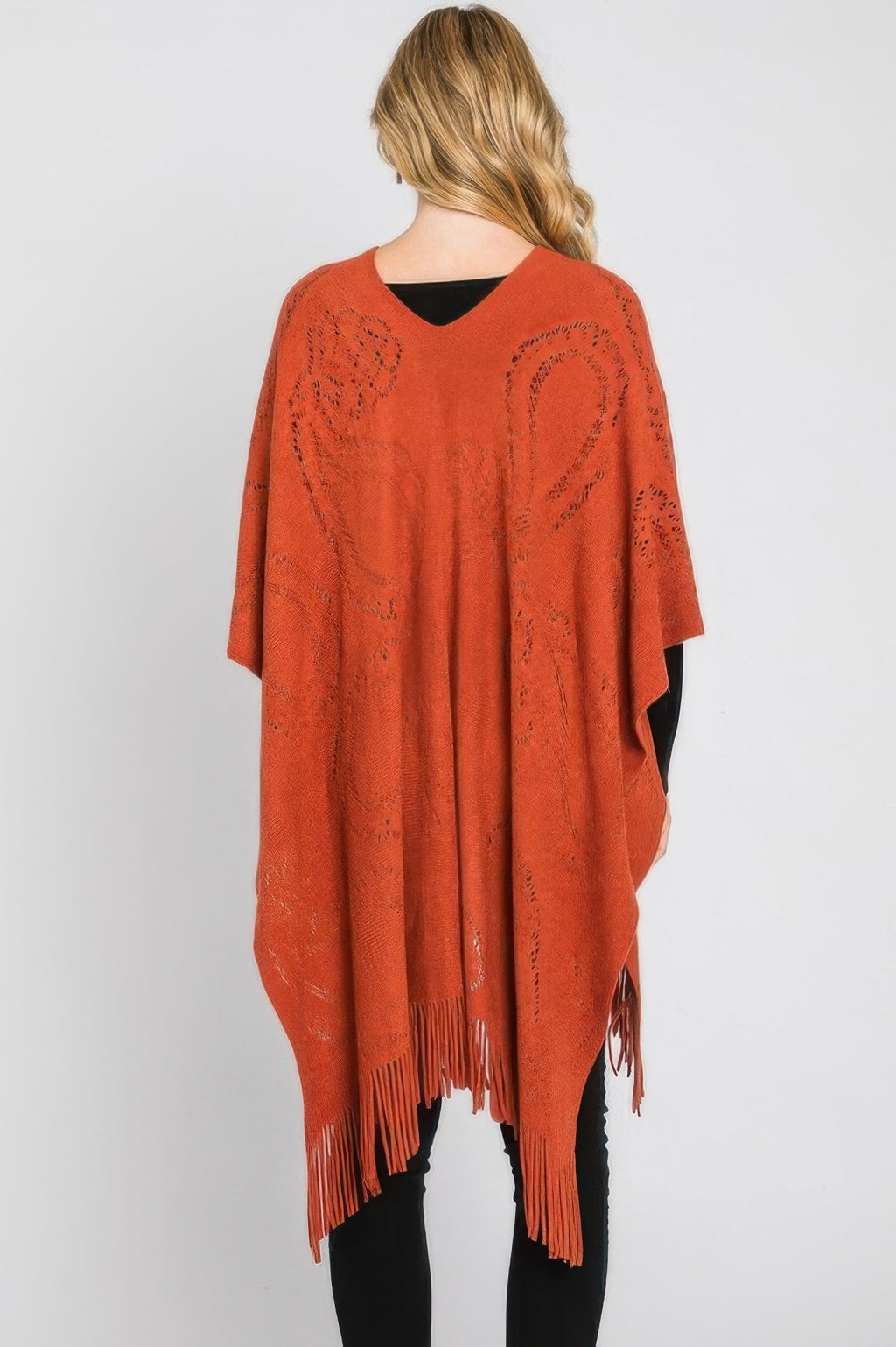 Rust orange paisley fringe poncho back view, flowing drape with tasseled hemline.