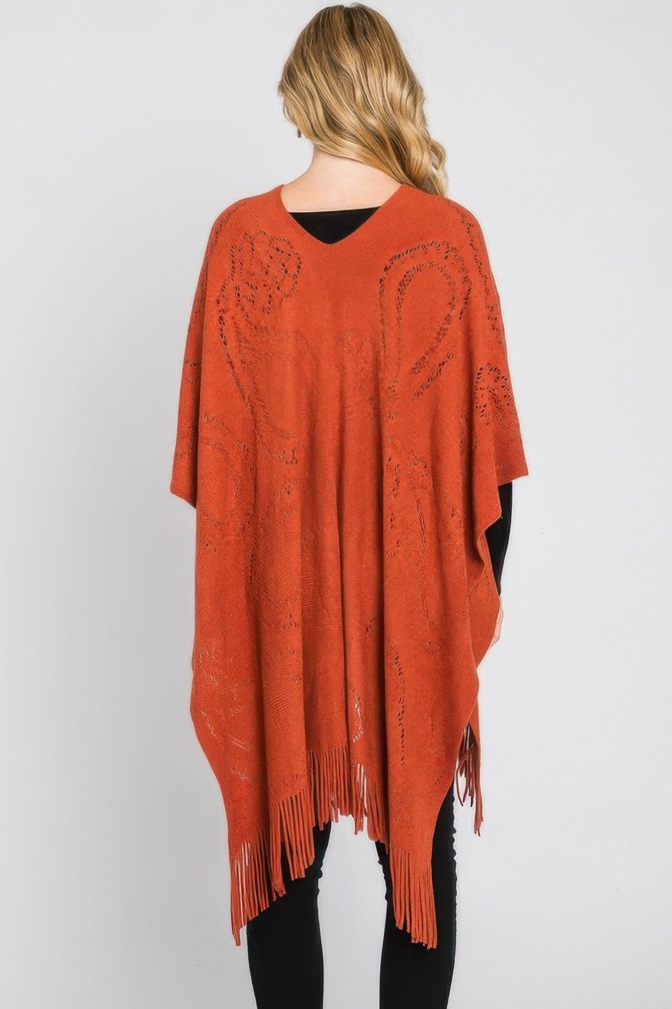 Rust orange paisley fringe poncho back view, flowing drape with tasseled hemline.