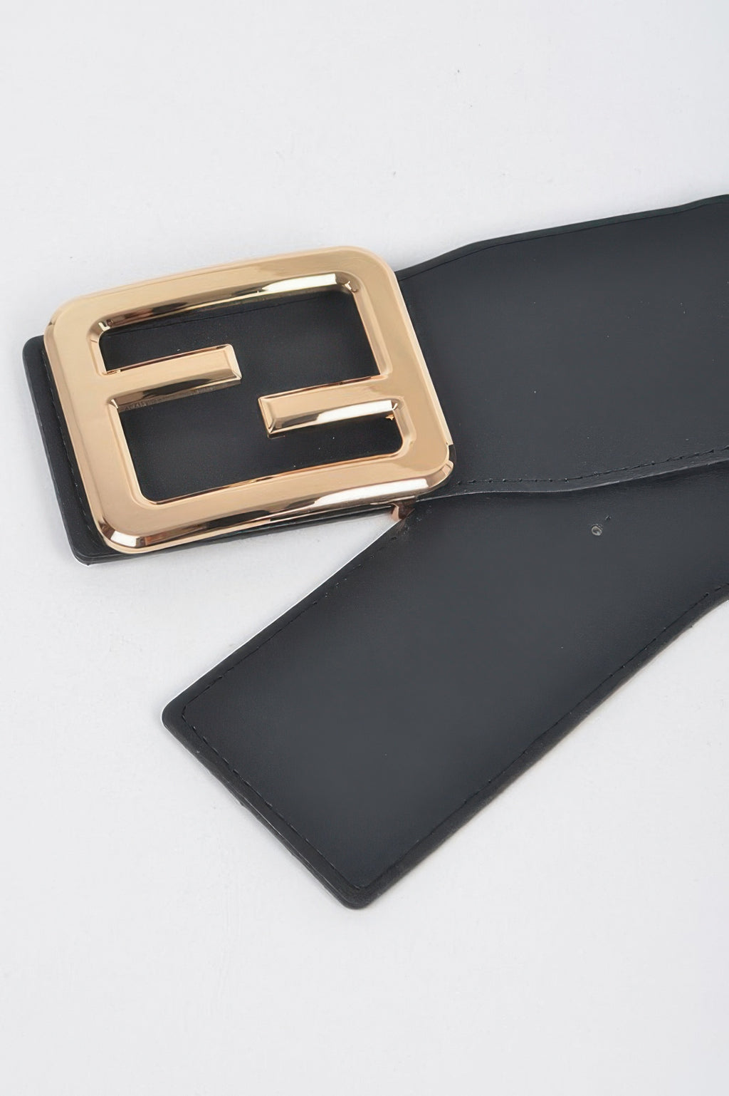 Black belt close-up: gold metal E buckle with rectangular frame